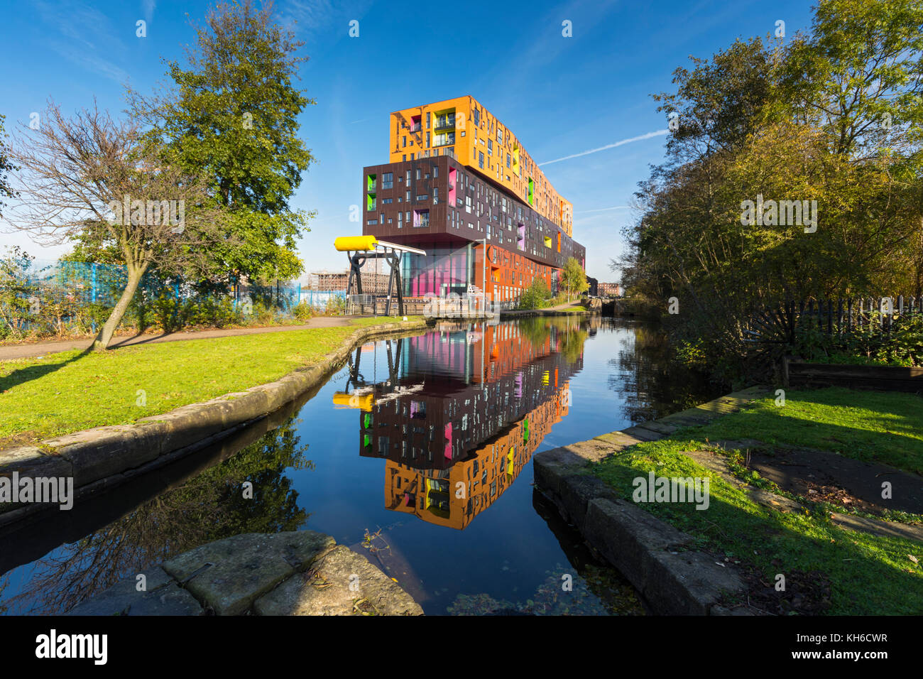 The Chips apartment building, by Will Alsop, and a bascule lifting bridge, reflected in the Ashton Canal, New Islington, Ancoats, Manchester, UK Stock Photo