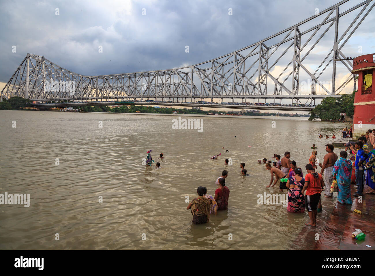 Howrah bridge - The historic cantilever bridge on river Hooghly with view of people at the adjoining river bank at Kolkata, India. Stock Photo