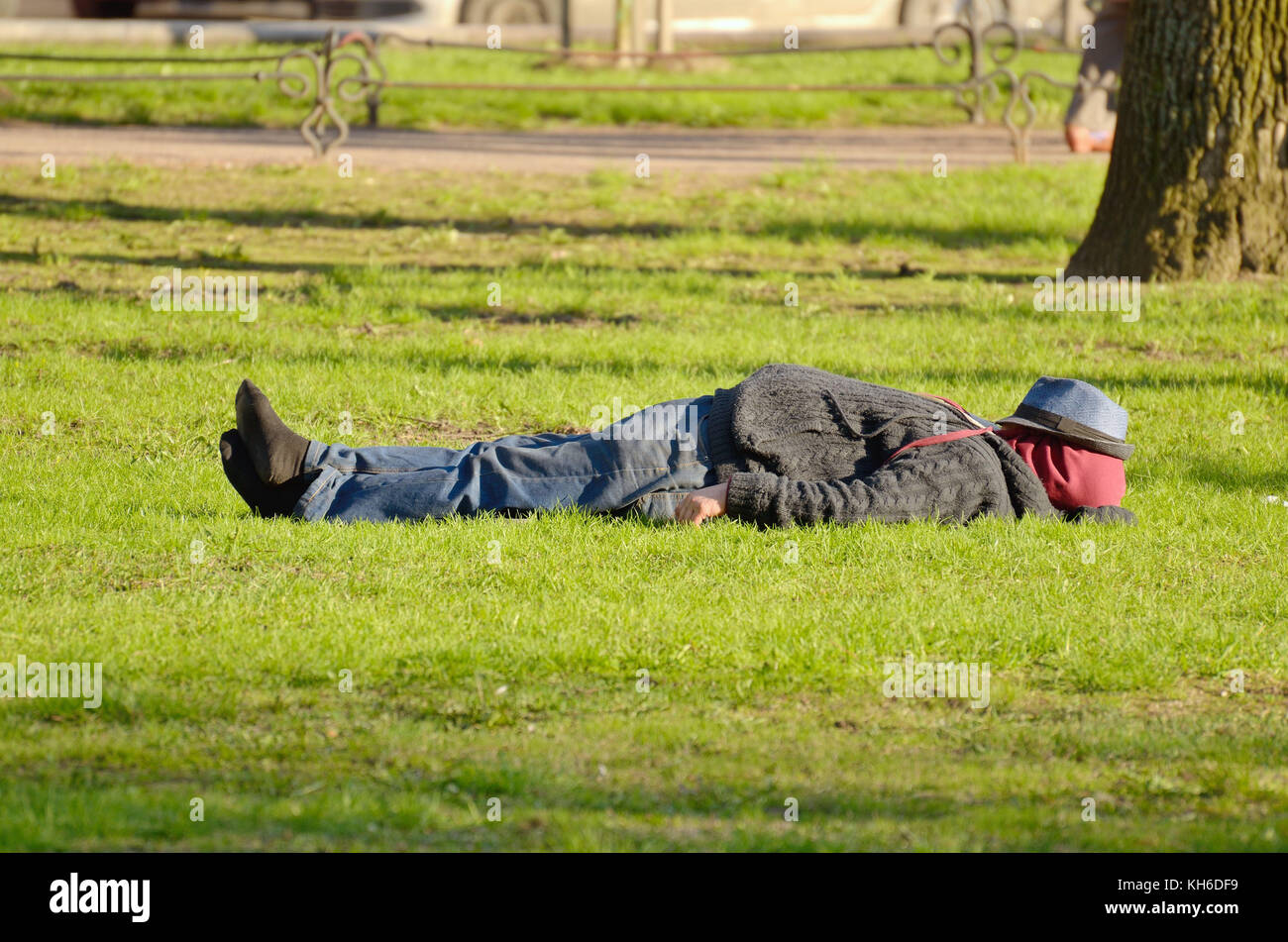 Russia.Saint-Petersburg.03.05.2016.The man was tired.He took off his shoes  and lay down on the grass to sleep Stock Photo - Alamy