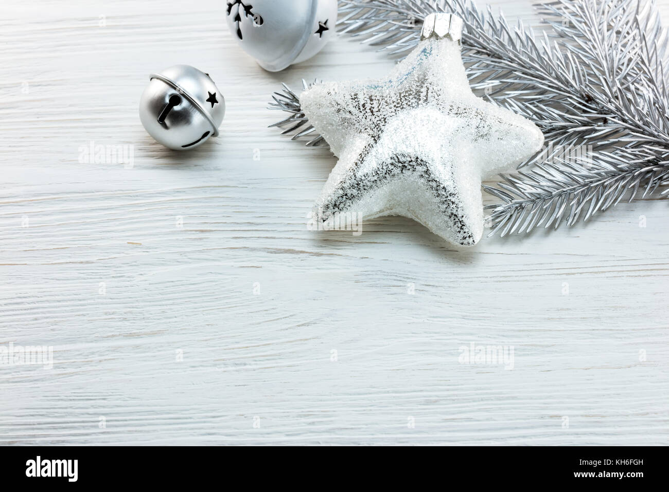 silver christmas tree decorations and fir tree branch on white wooden ...