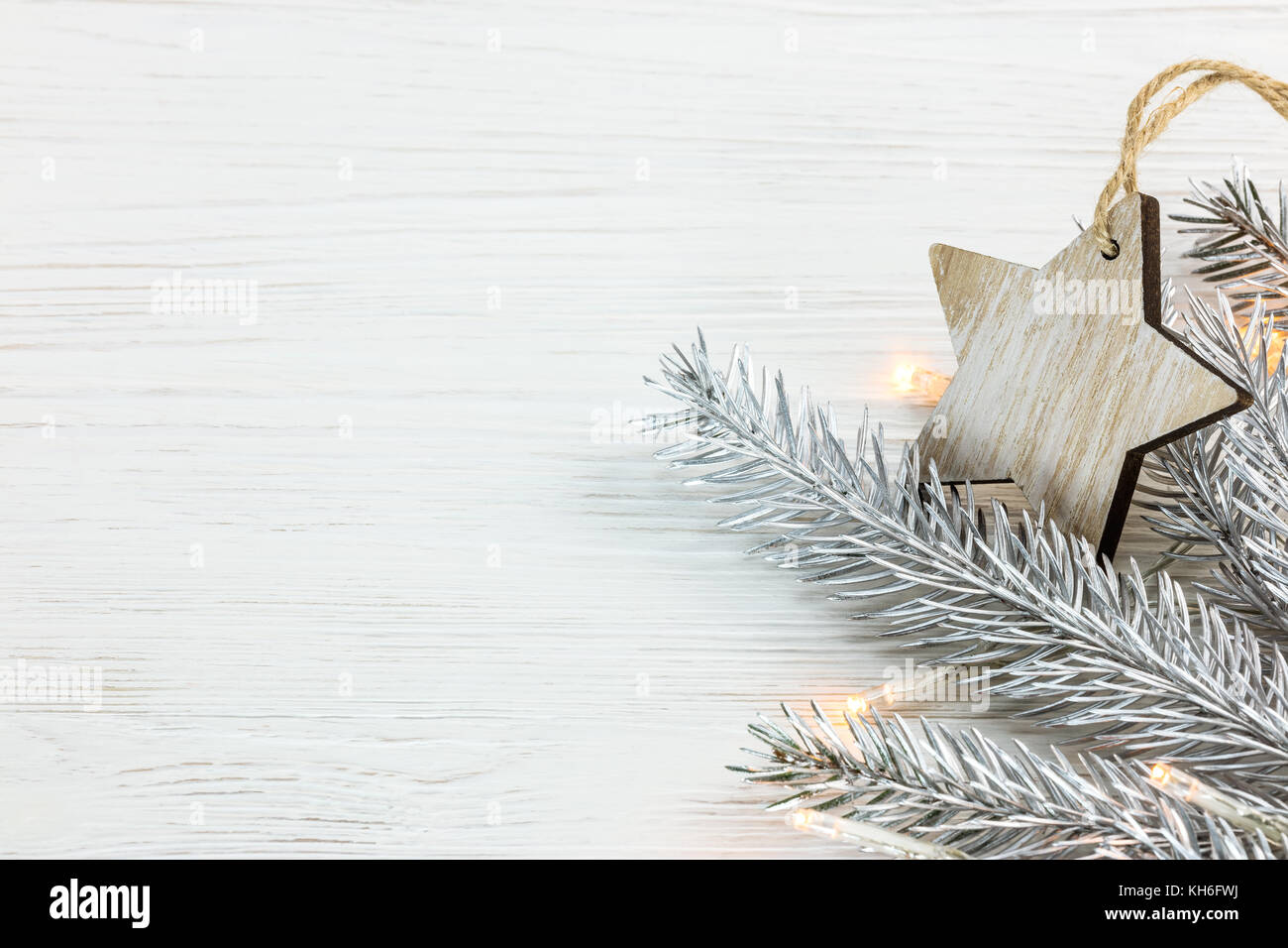 silver christmas fir tree branch with light garland and rustic wooden ...