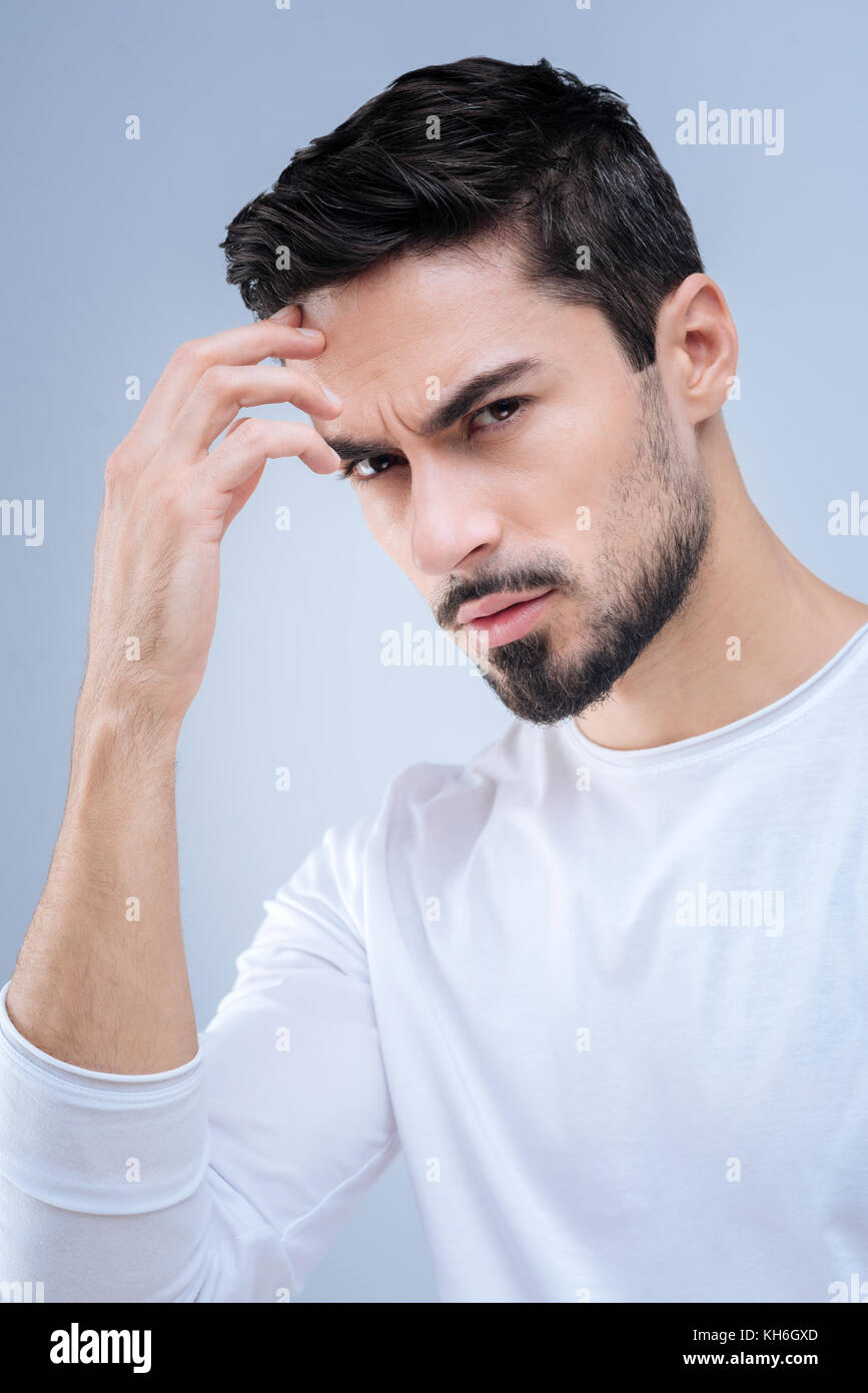 Concentrated man looking worried while standing and frowning Stock Photo