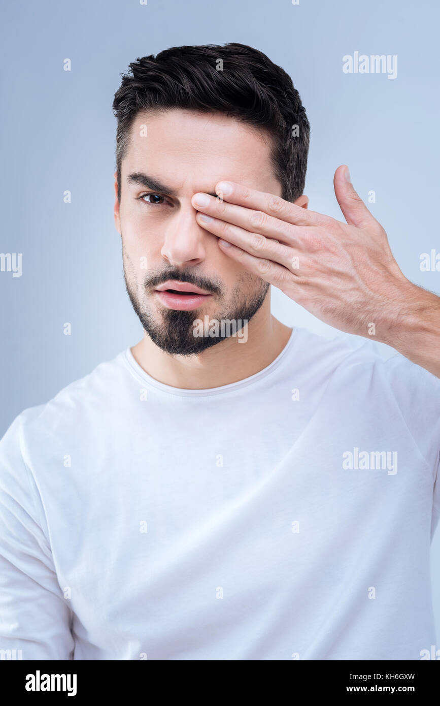 Serious man closing his eye and realizing the condition of his eyesight Stock Photo