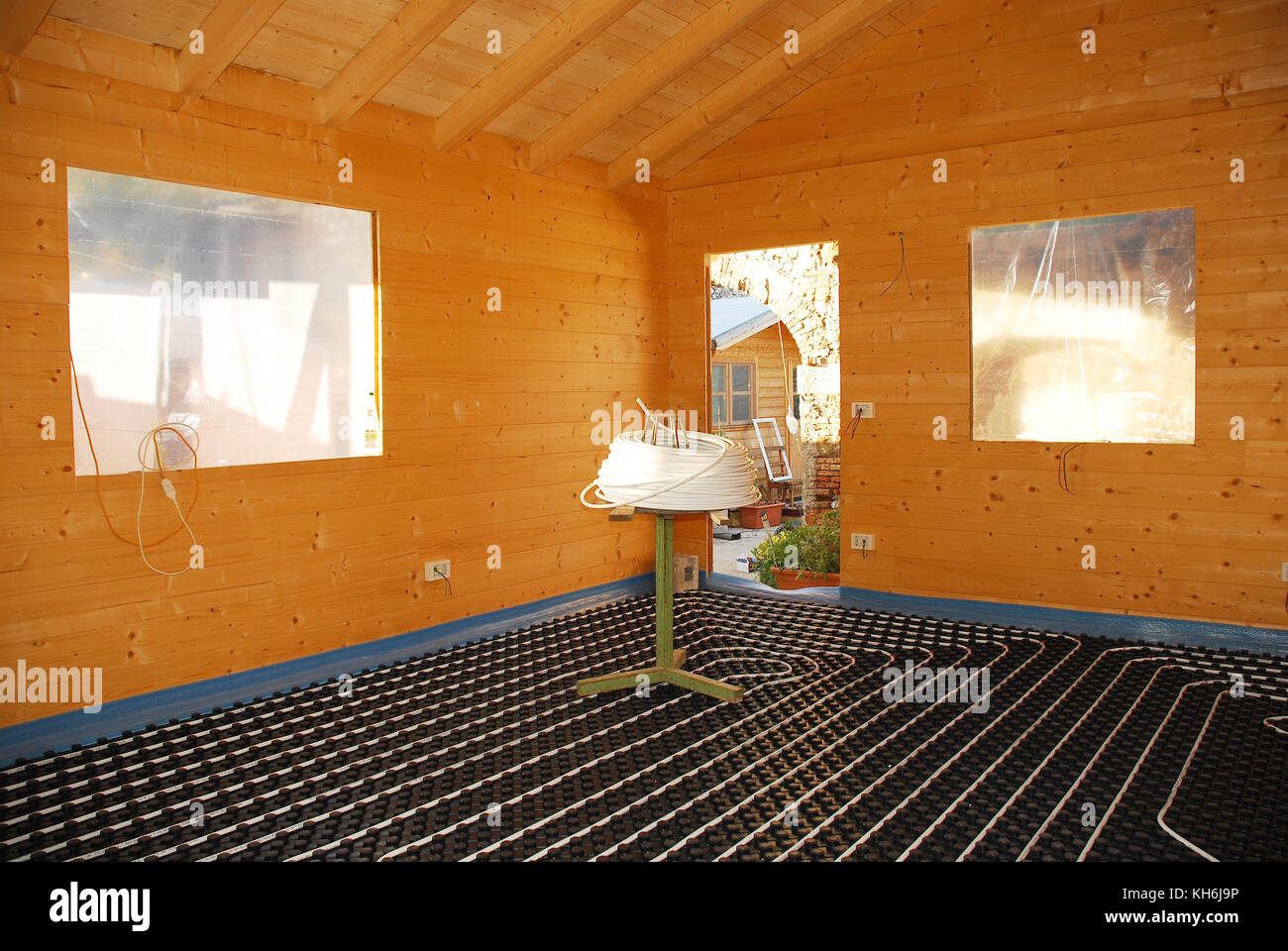 A hydronic closed loop underfloor heating system laid out on molded insulated panel in EPS with a spooling table inside a partially constructed wooden Stock Photo