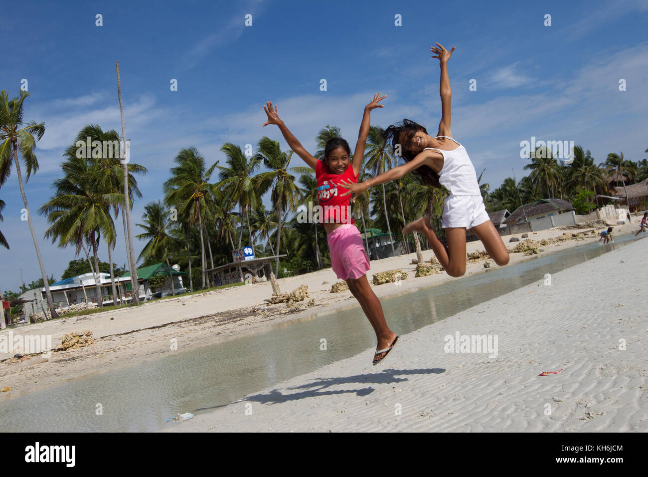 Two Filipino Girls Jump In The Air Along Santa Fe Beach Bantayan Island Cebu Philippines Stock