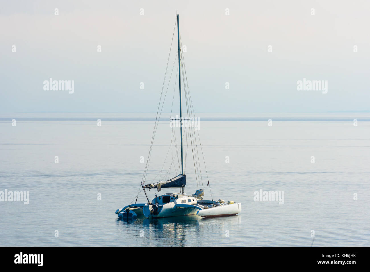 Catamaran is moored in calm sea of Adriatic sea. Sailboat with tender or and calm sea in the evening. Silba, Croatia. Stock Photo
