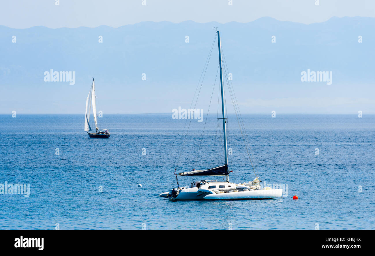 Catamaran is moored in calm sea of Adriatic sea. Sailboat with or and windy sea. Silba, Croatia. Stock Photo