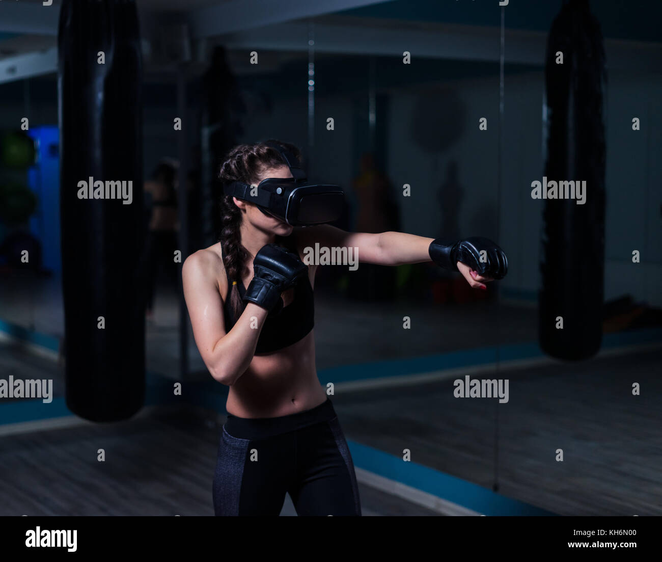 Young fighter boxer fit girl in VR glasses wearing boxing gloves Stock Photo