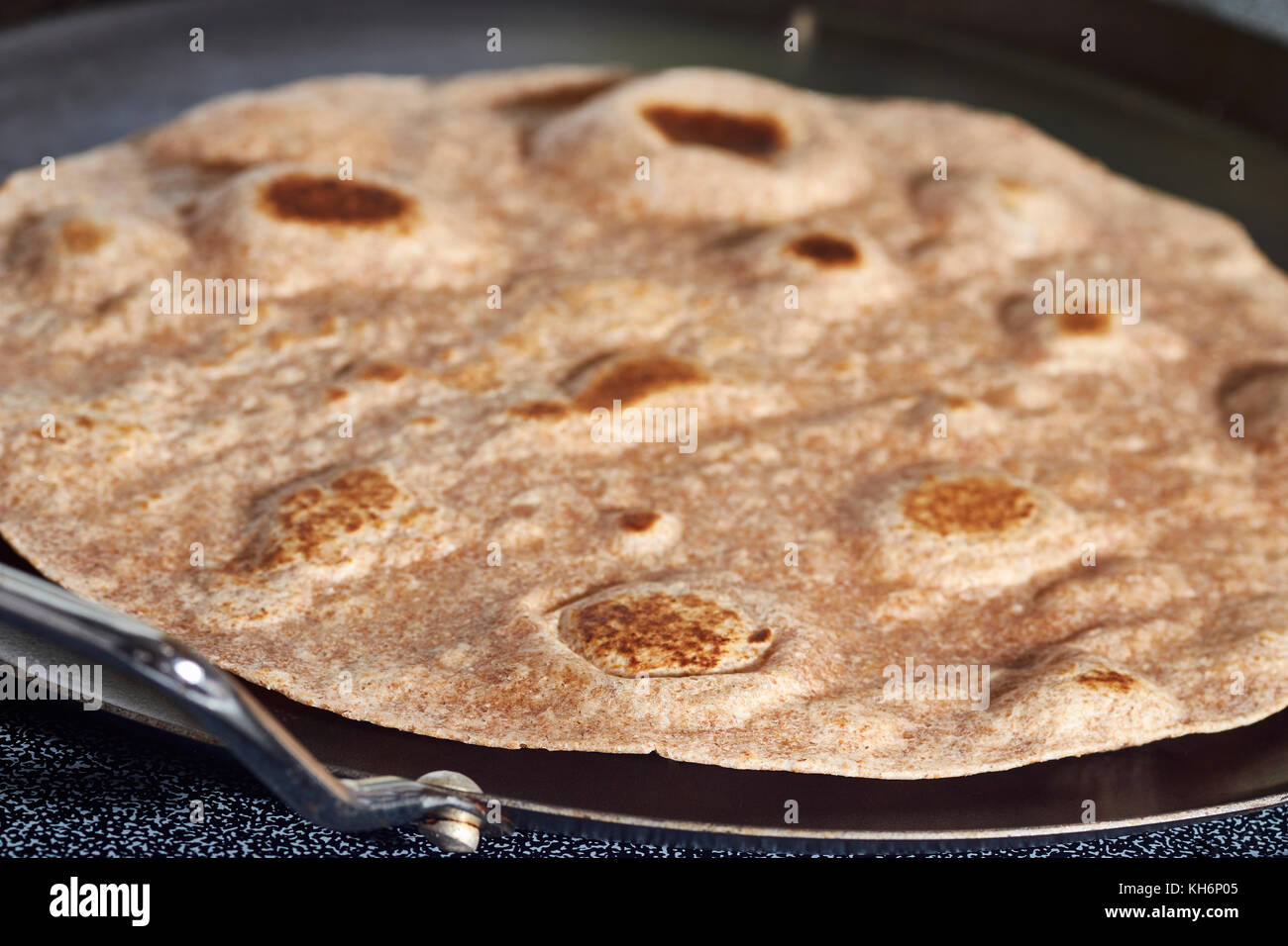 a whole wheat flour tortilla warming on the comal - a type of Mexican grill Stock Photo