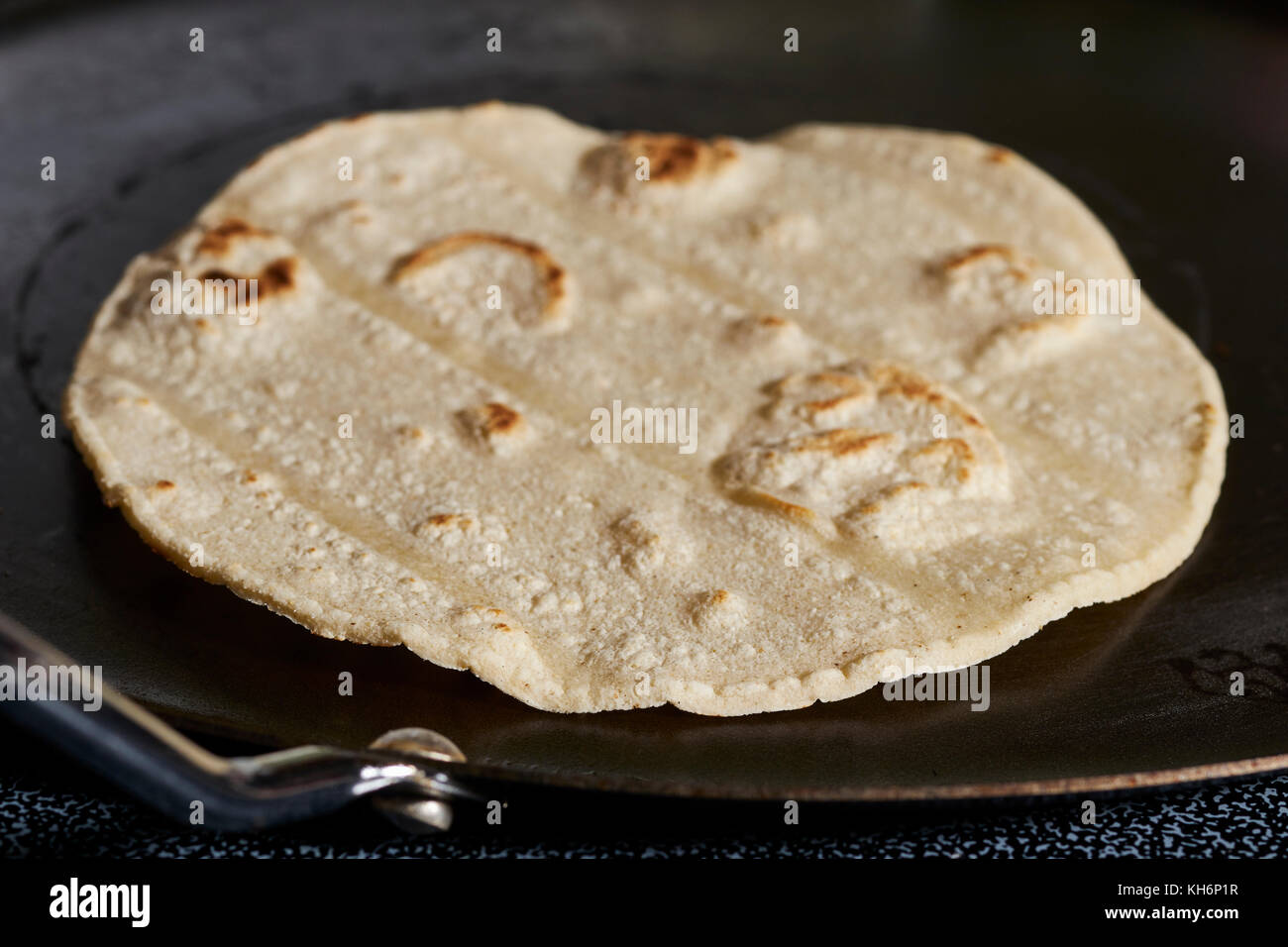 A corn tortilla cooking on a comal Stock Photo