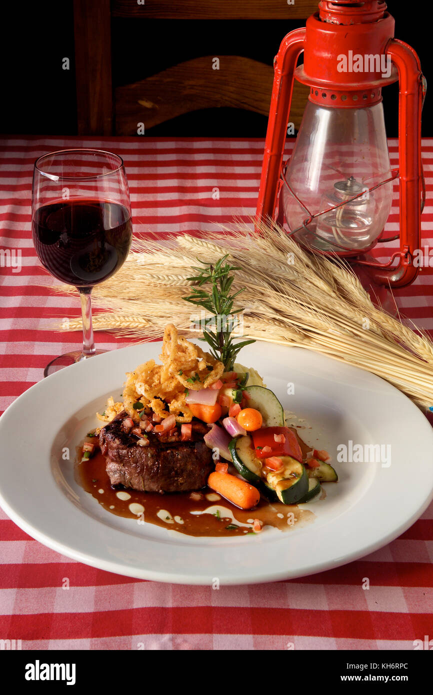 All American steak dinner served with red wine on red gingham table ...
