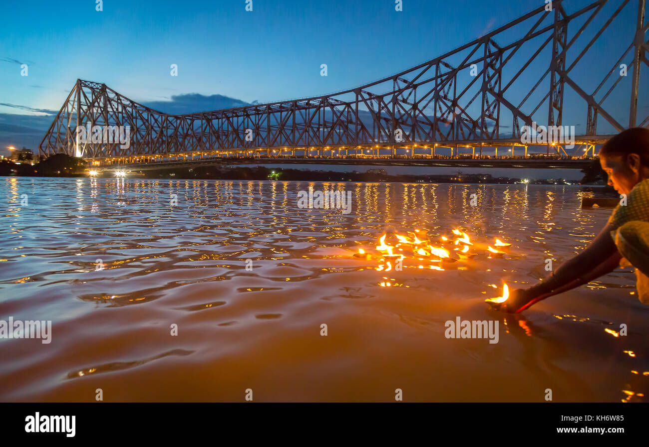 Howrah bridge Kolkata - Aged woman perform rituals of sailing clay diya ...