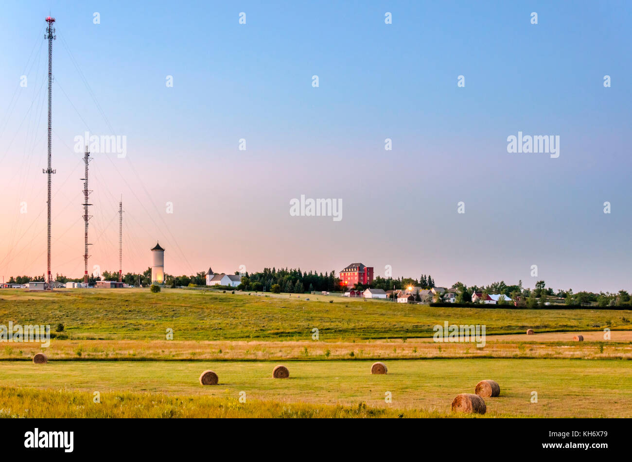 The town with a white tower and a church, on top of a hill, haystacks ...