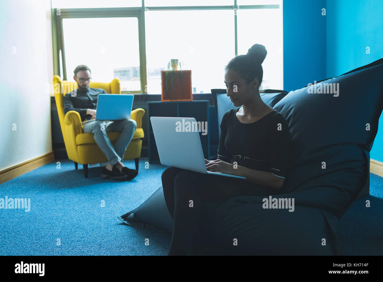 Executives sitting on arm chair and using laptop in office Stock Photo