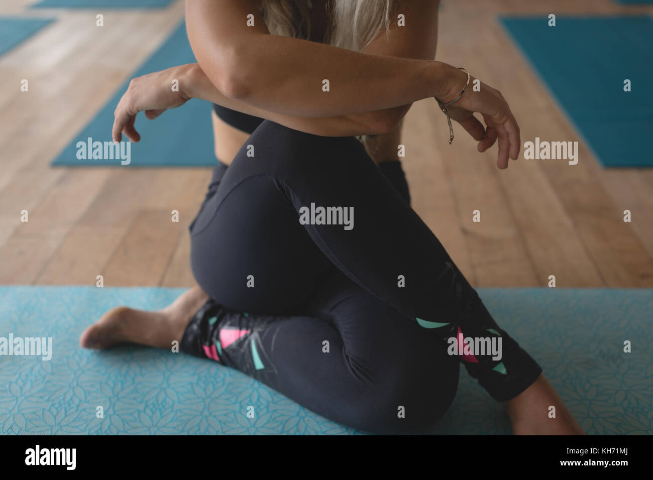 Beautiful woman sitting at yoga mat in yoga class Stock Photo - Alamy