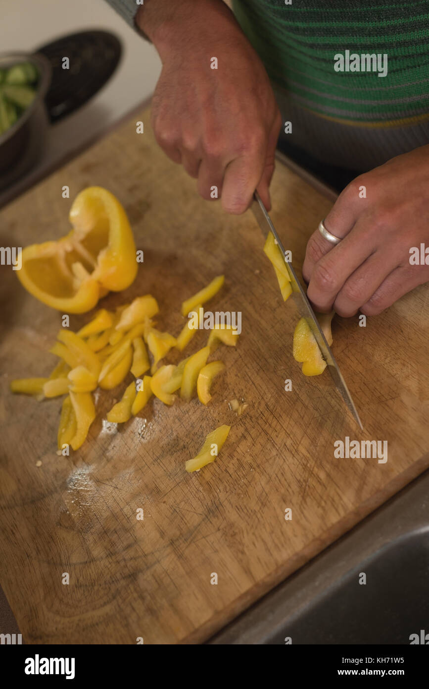 Man chopping yellow bell pepper on cutting board in kitchen Stock Photo ...