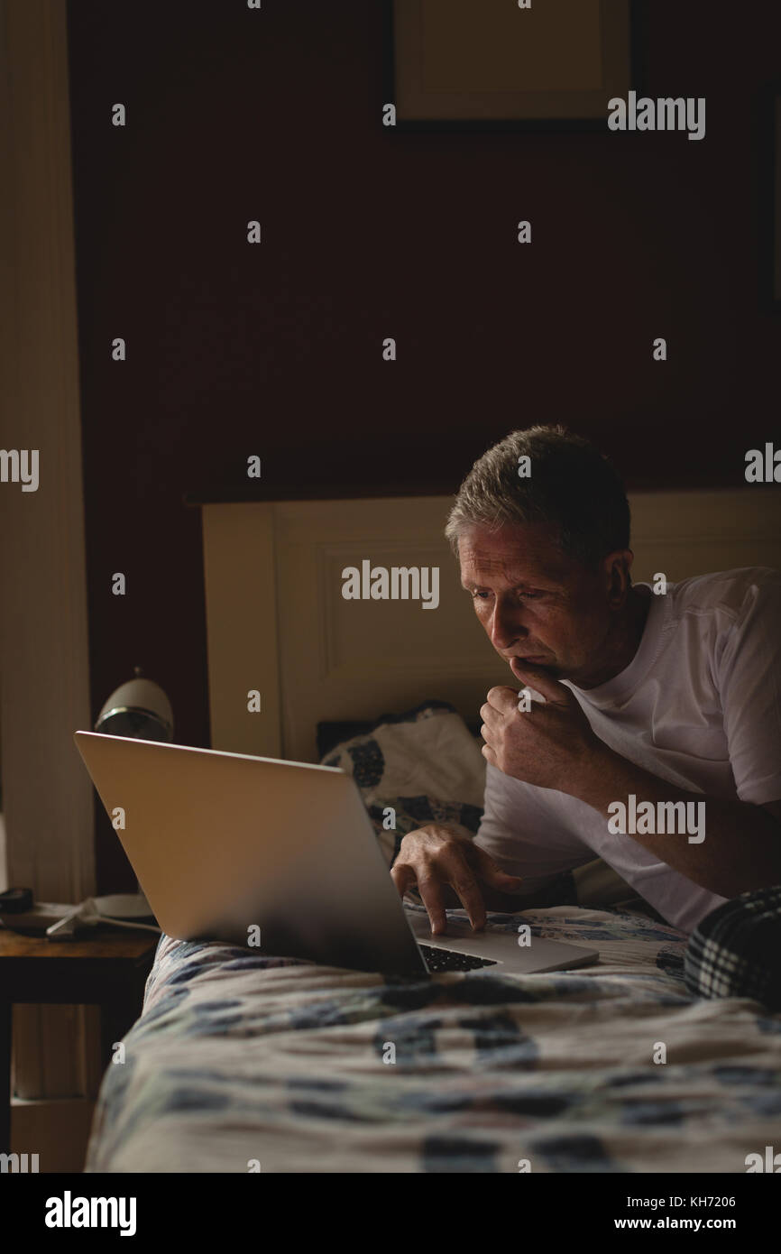 Senior man using laptop in bedroom at home Stock Photo - Alamy