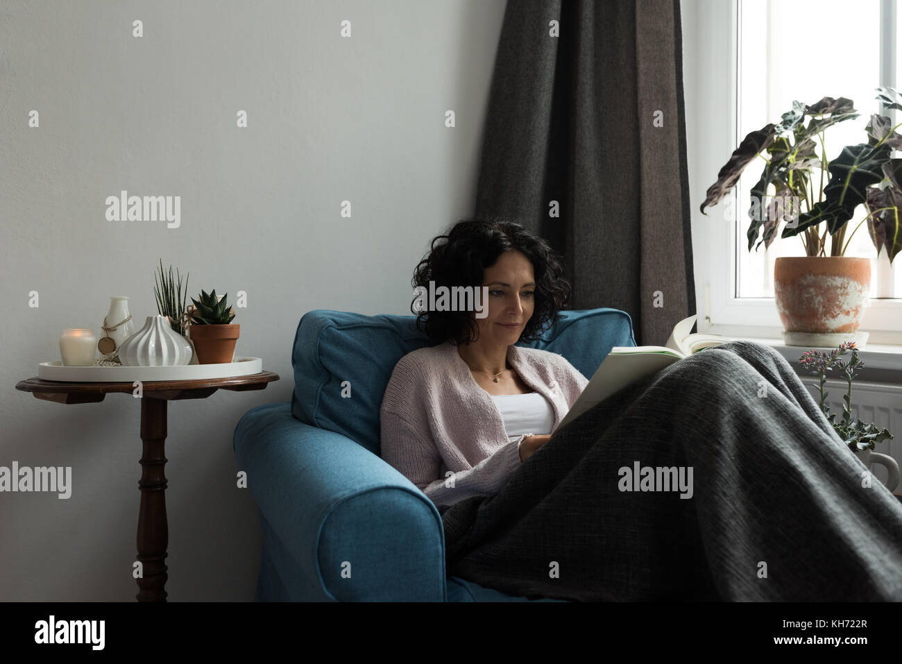 Beautiful woman relaxing on sofa and reading book at home Stock Photo ...