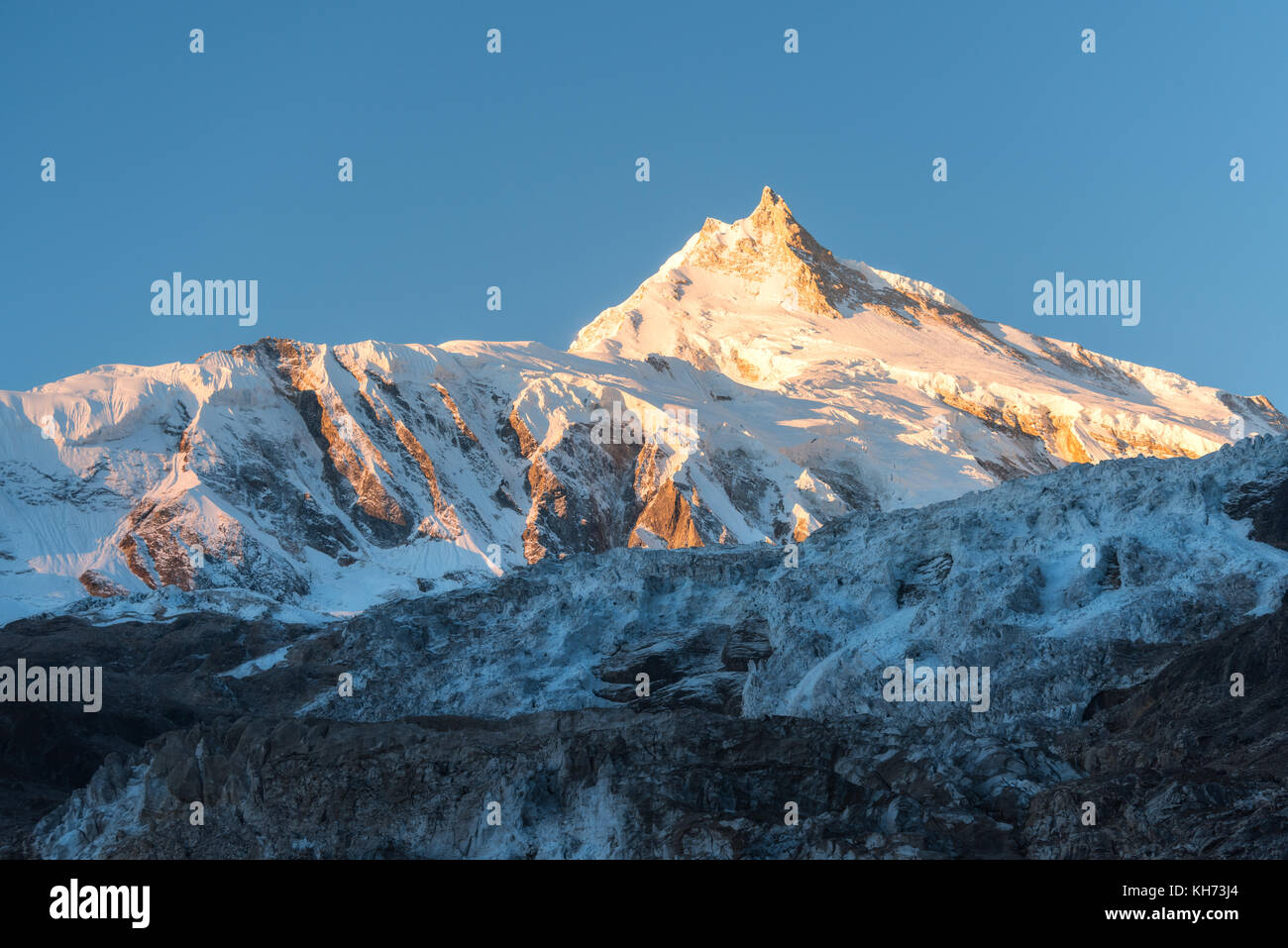 Beautiful view of snow-covered mountain at colorful sunrise in Nepal. Landscape with snowy peaks of Himalayan mountains, glacier and blue sky in the m Stock Photo