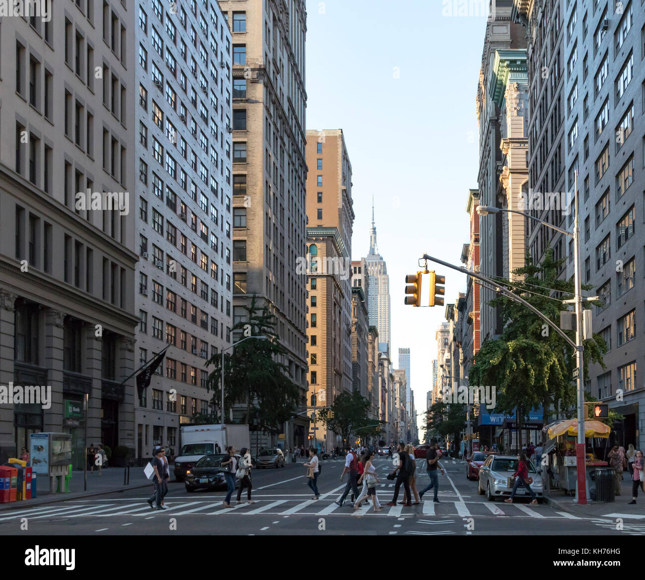 NEW YORK CITY - CIRCA 2017: People walk across a busy intersection on Fifth Avenue with the Empire State Building in the background skyline of Manhatt Stock Photo