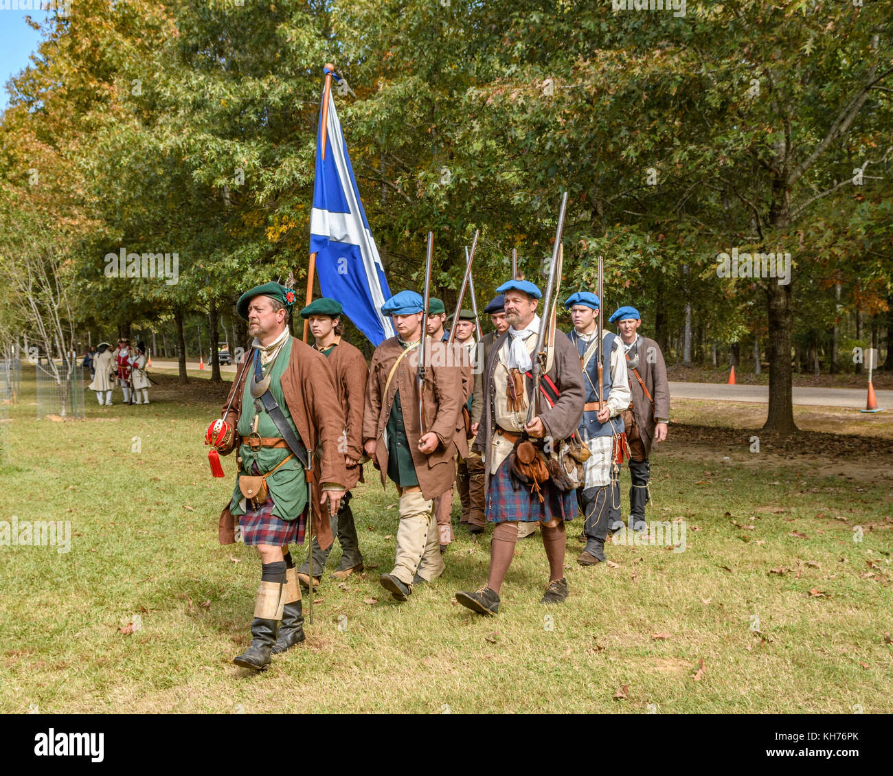Reenactment actors dressed as Scottish army soldiers of the early 1700's marching with the flag of Scotland. Stock Photo