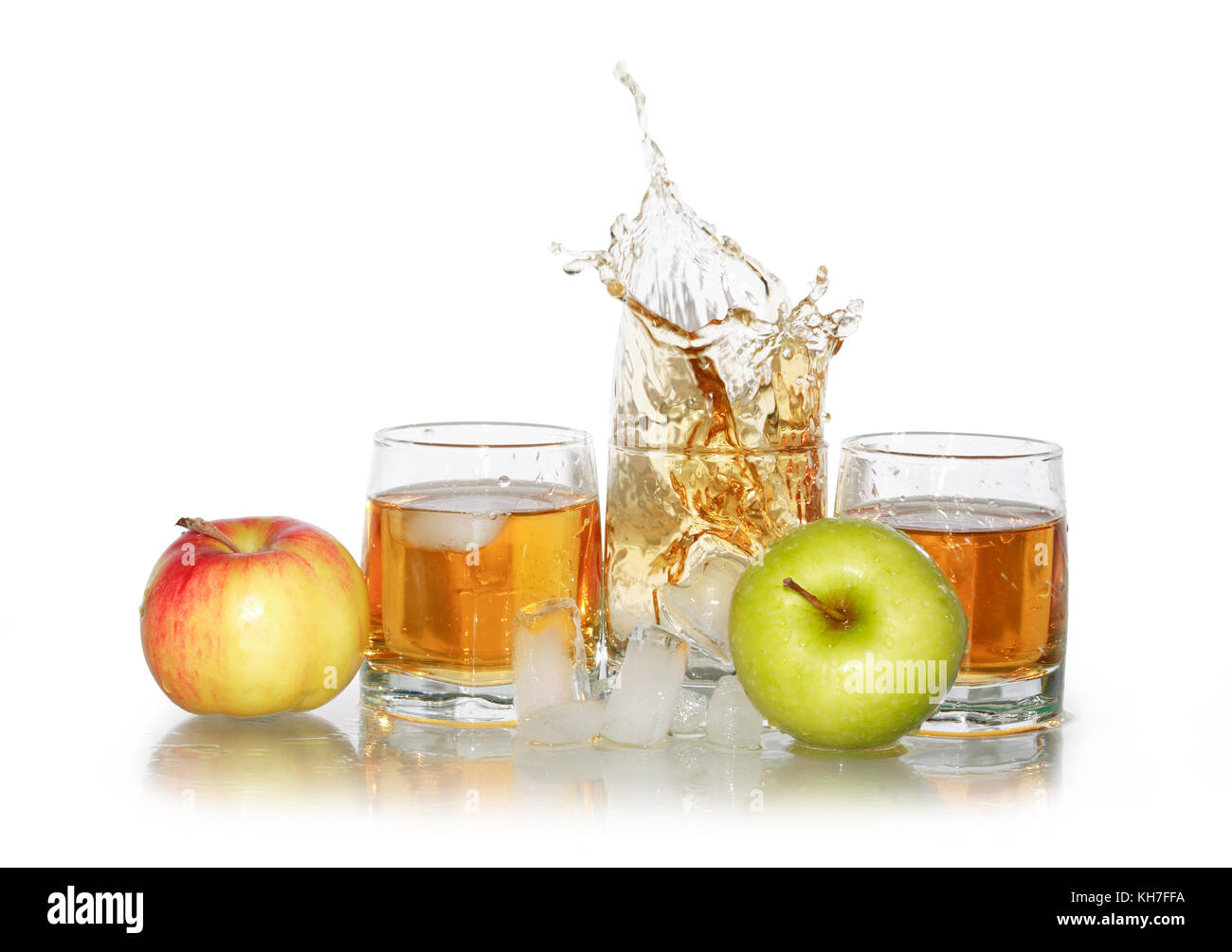 Three glasses with splashing apple juice near ice cubes and apples ...