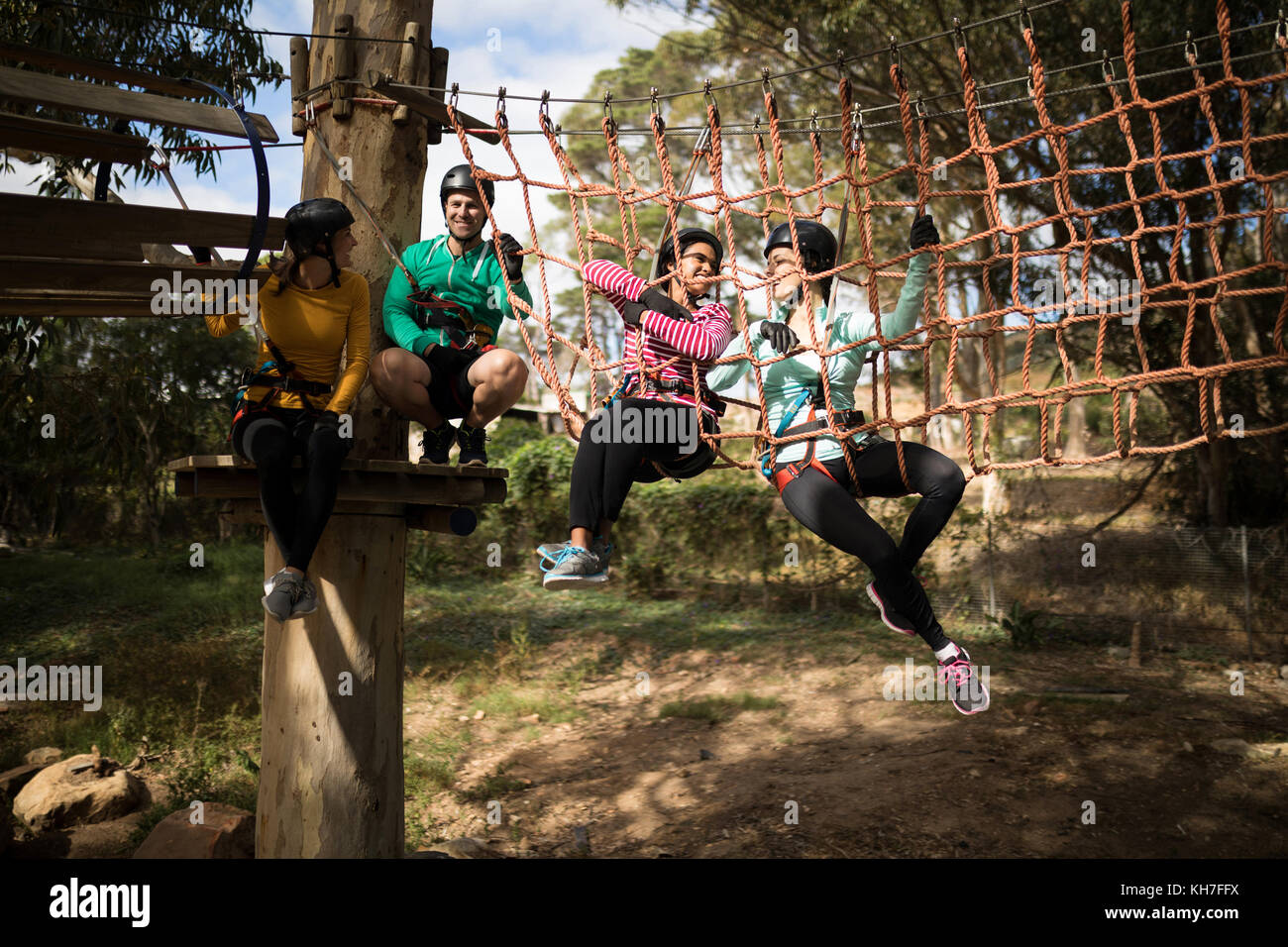 Happy friends relaxing on rope bridge in adventure park Stock Photo - Alamy