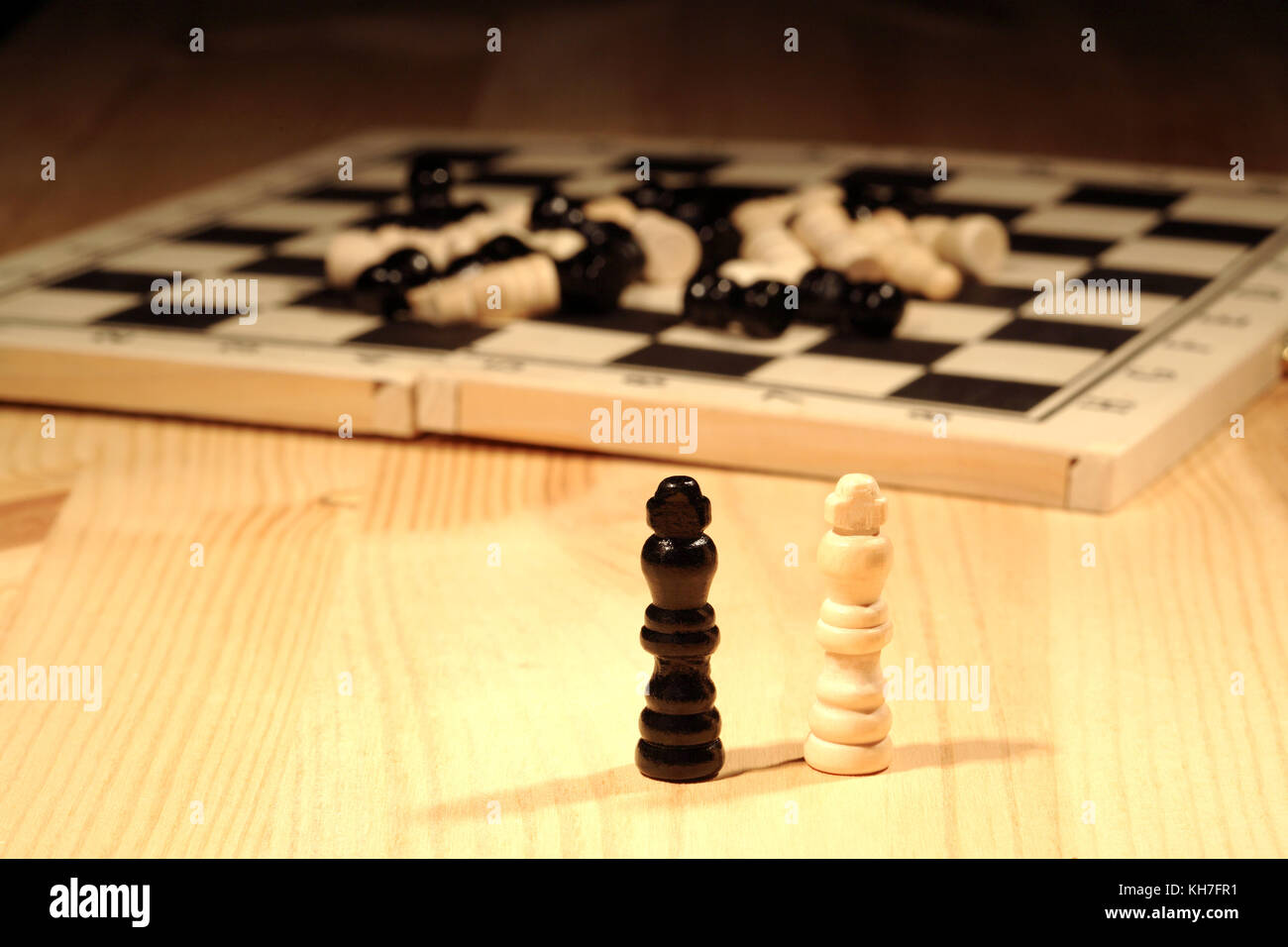 Chess concept. Two chessmen standing near chess board on wooden background Stock Photo