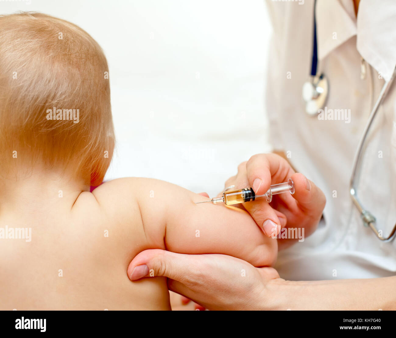 Doctor giving a child an intramuscular injection in arm, shallow DOF ...