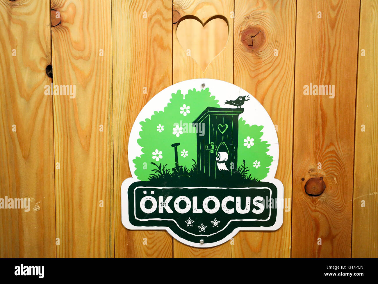 Leipzig, Germany. 13th Nov, 2017. Picture of the door of an outhouse made out of wood, with the de rigeur heart-shaped hole and the company's logo, taken in Leipzig, Germany, 13 November 2017. The toilet services provider Okolocus rents the self-made outhouses for weddings, festivals or for owners of small gardens. People who need to go to the toilet sit on toilet seats made out of wood. Underneath is a plastic drum with a capacity of between 50 and 60 liters. After doing the business a shovelful of wood shavings is thrown into the drum. Okolocus takes care of the disposal of the contents. Cre Stock Photo