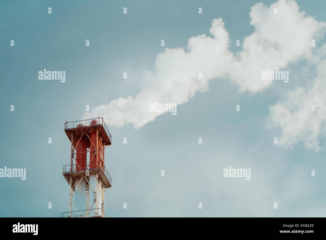Close-up of red and white chimney with a cloud of white smoke against ...