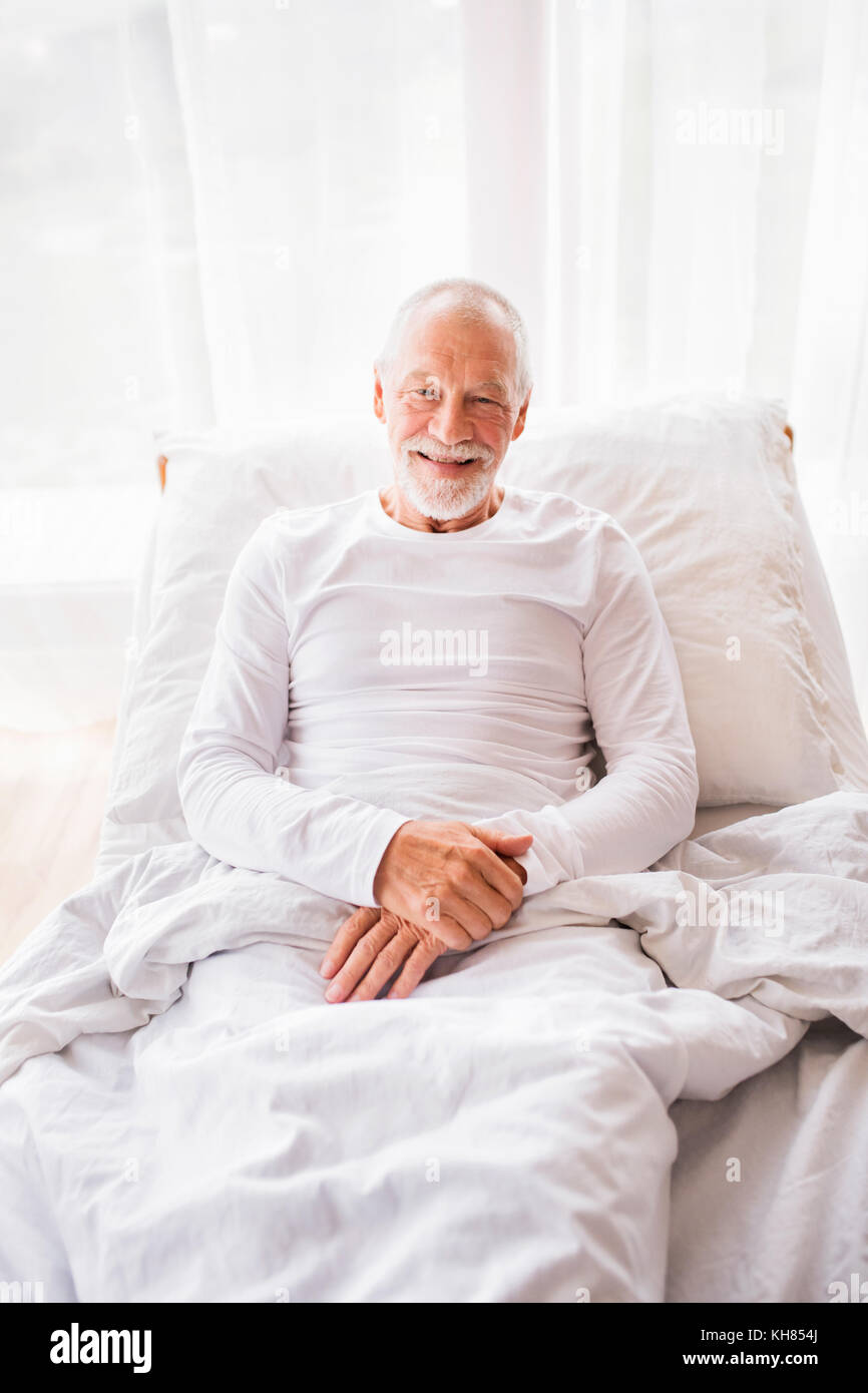 Senior man lying in bed at home. Stock Photo