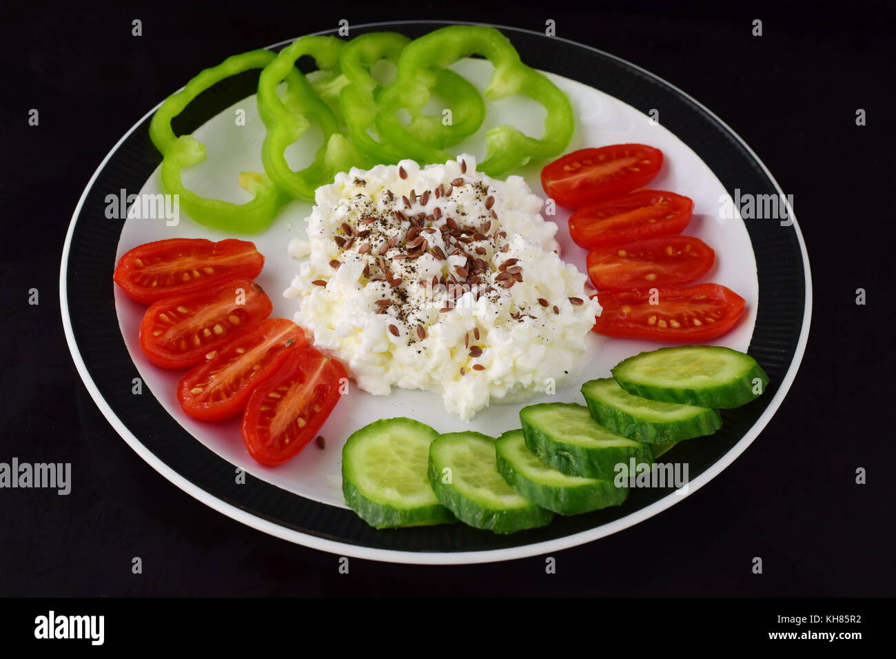 Easy breakfast with paprika, tomato, cucumber with cottage cheese and flax seeds on a plate on a dark background Healthy eating concept. Healthy food Stock Photo
