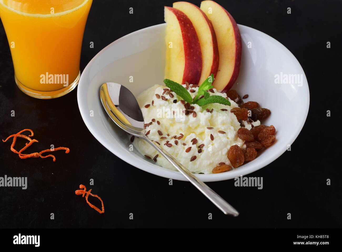 Healthy breakfast: cottage cheese with flax seeds, raisins, fresh apples and a glass of fresh orange juice. Healthy eating concept Stock Photo