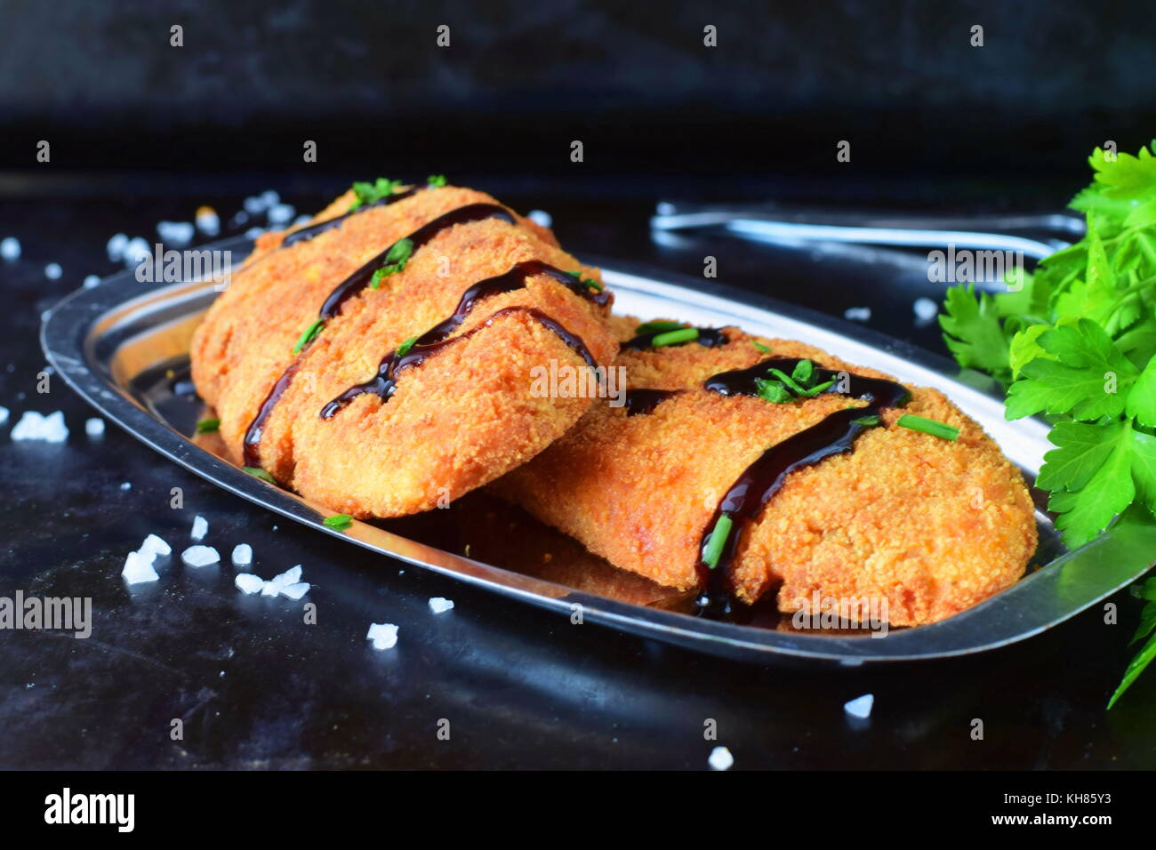 Carrot fritters on a metal plate on a black abstract background. Healthy eating concept Stock Photo