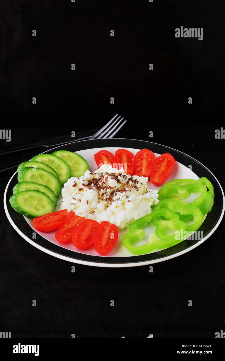 Easy breakfast with paprika, tomato, cucumber with cottage cheese and flax seeds on a plate on a dark background Healthy eating concept. Healthy food Stock Photo