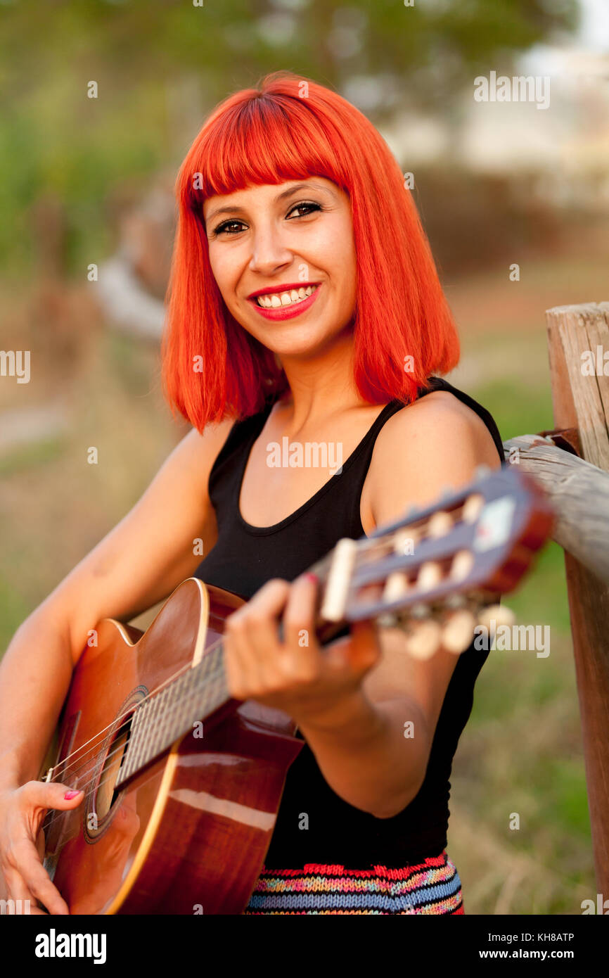 Red hair woman playing guitar in the countryside Stock Photo - Alamy