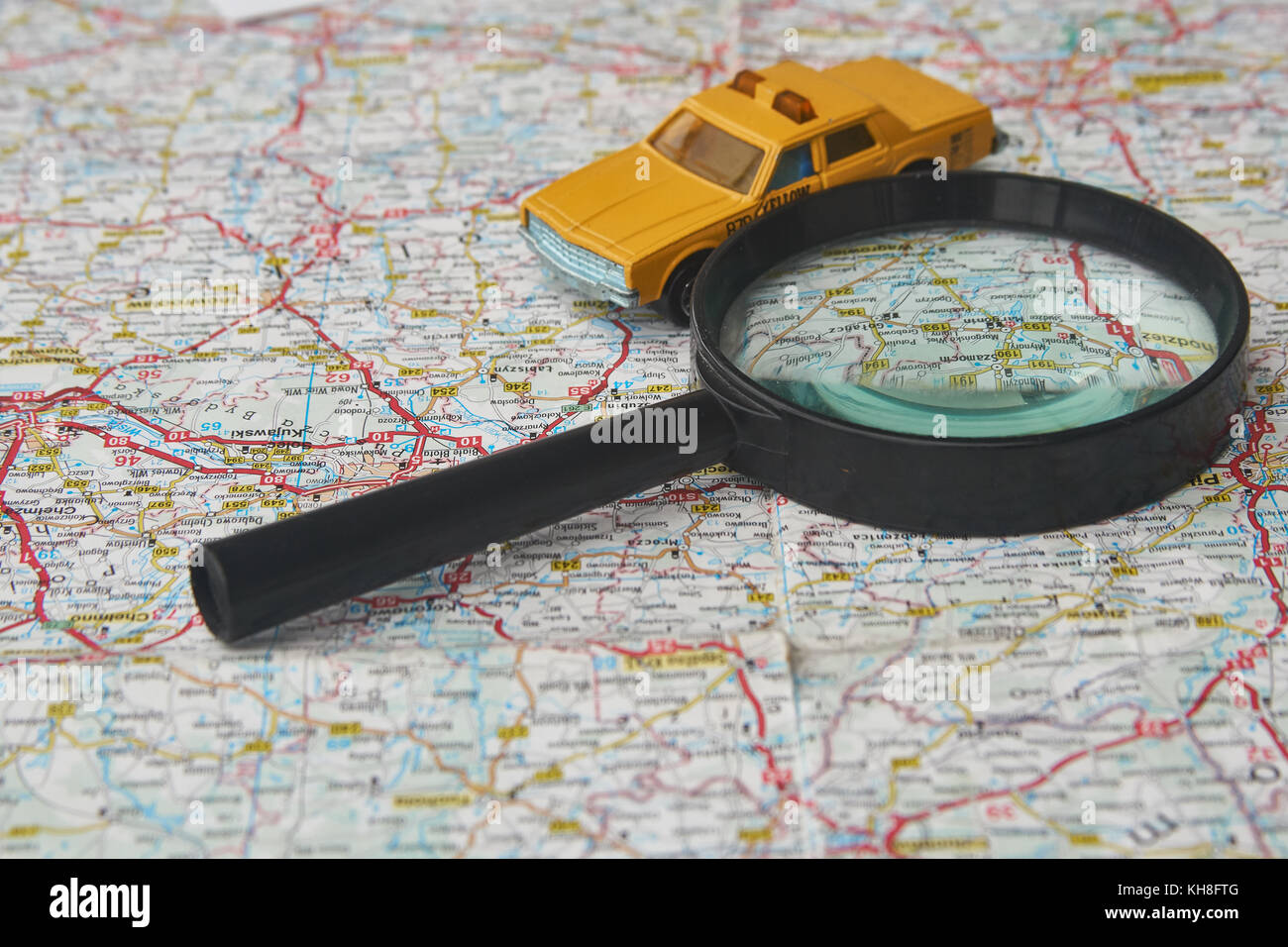 Magnifying glass and toy car on a map Stock Photo