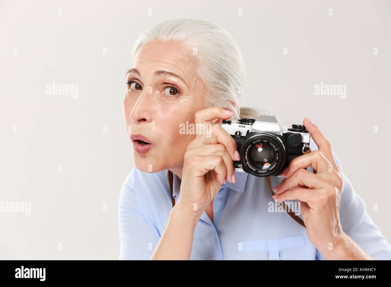 Surprised mature beautiful in casual woman holding retro camera islated over white Stock Photo