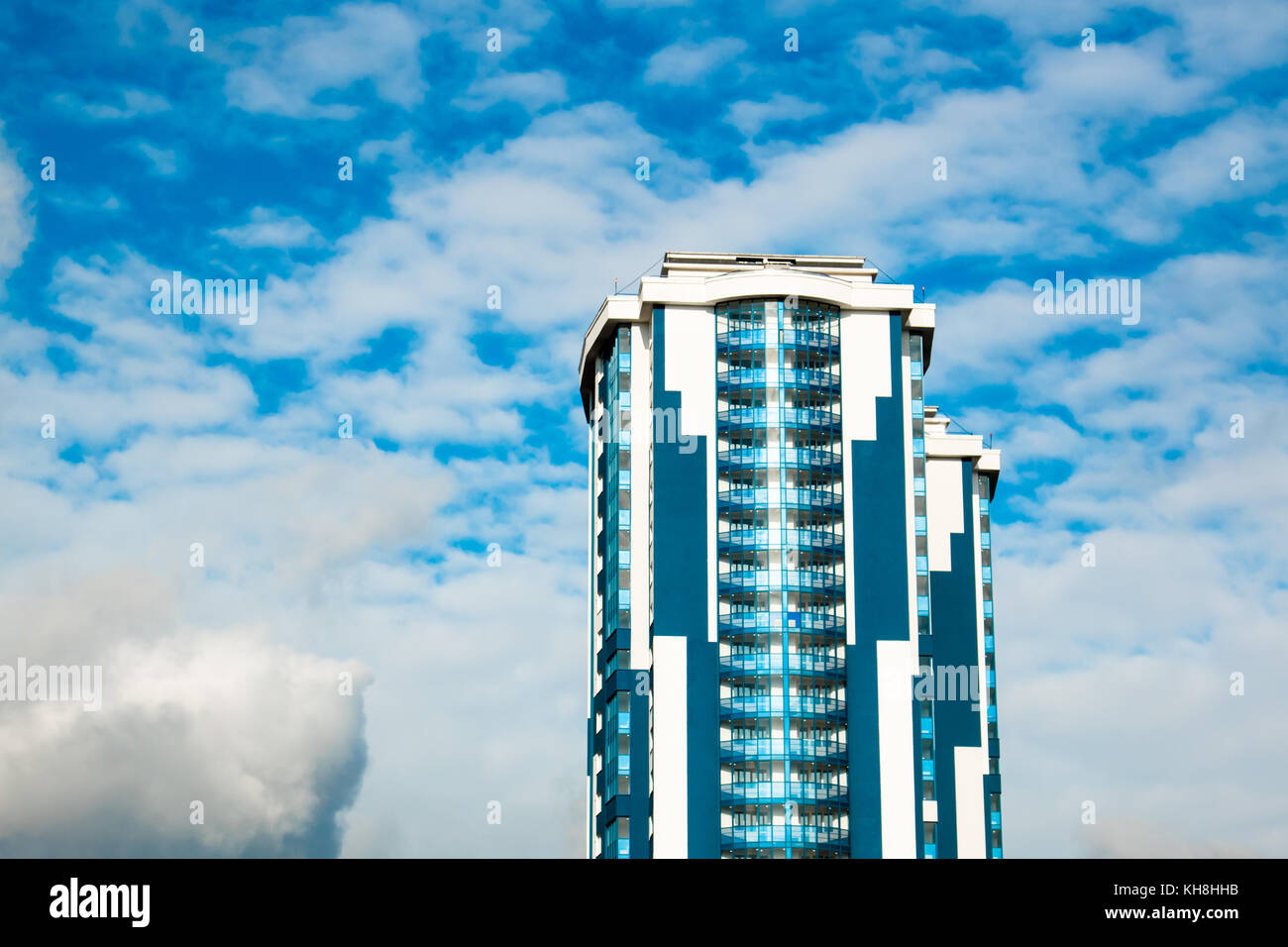 High-rise building with a glass facade against a bright blue sky with ...