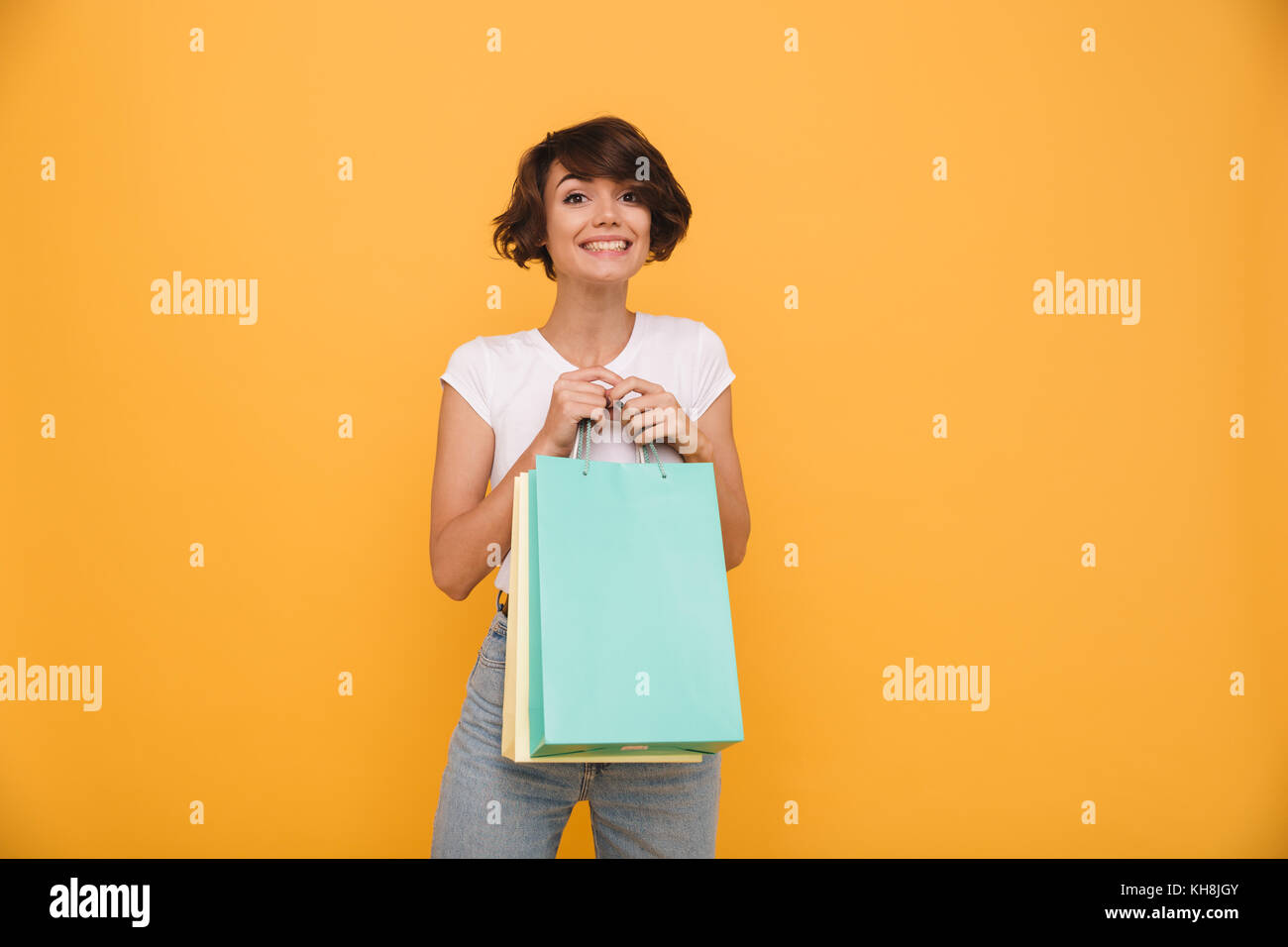 Portrait of a smiling satisfied girl holding shopping bags and looking ...