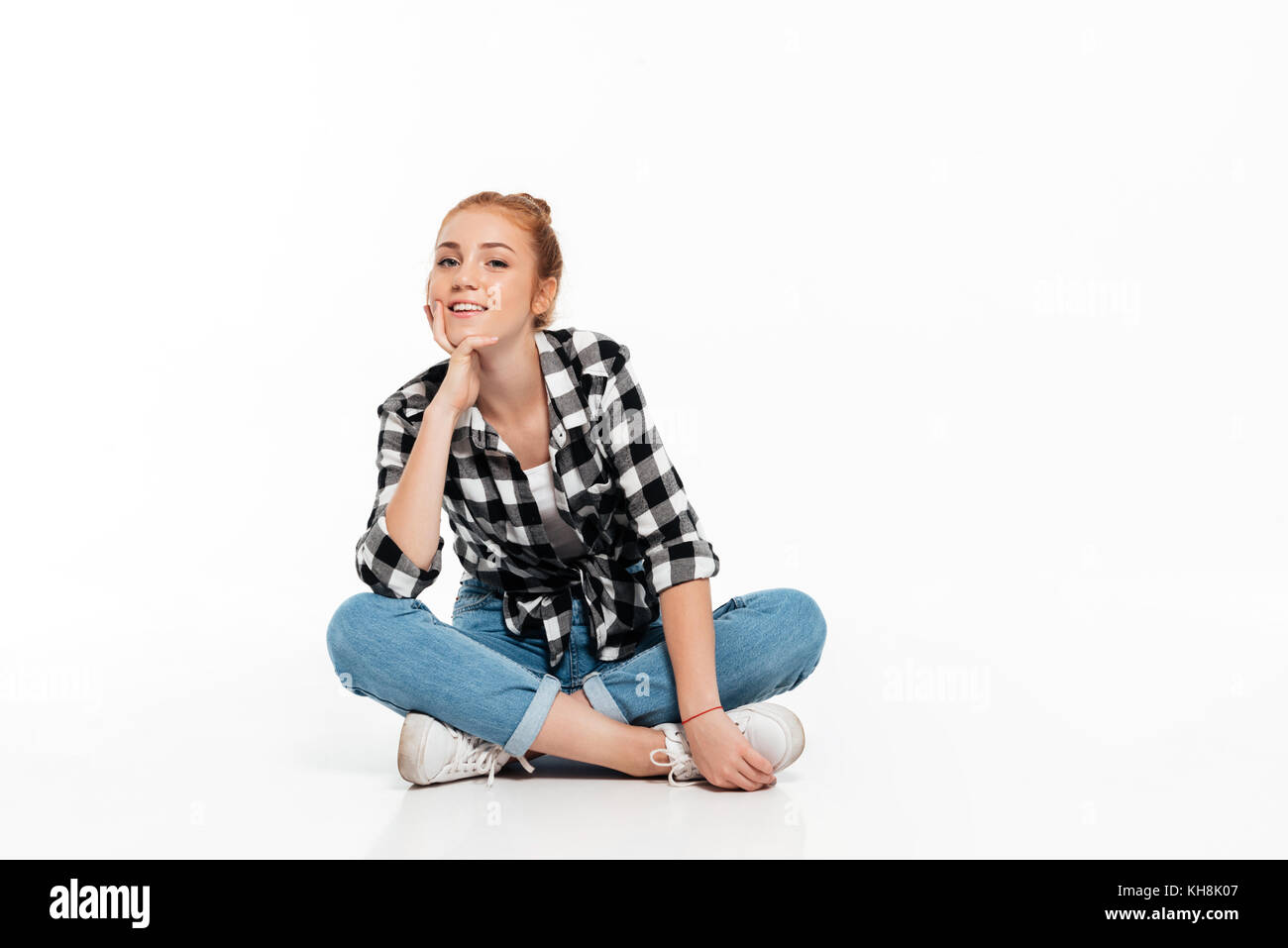 Smiling ginger woman in shirt and jeans sitting on the floor and ...