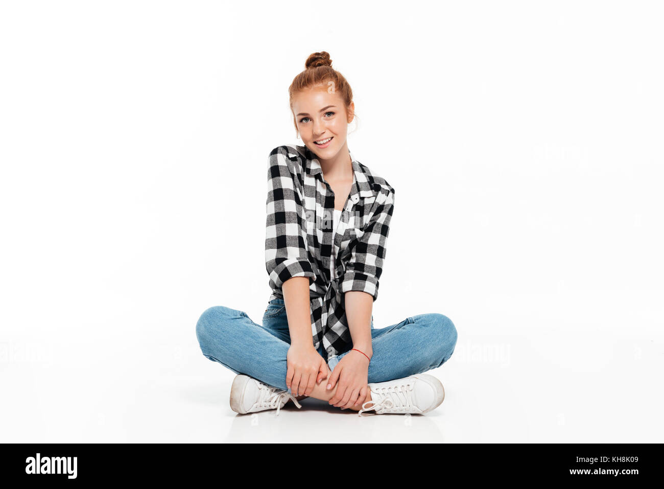 Cheerful ginger woman in shirt and jeans sitting on the floor and ...