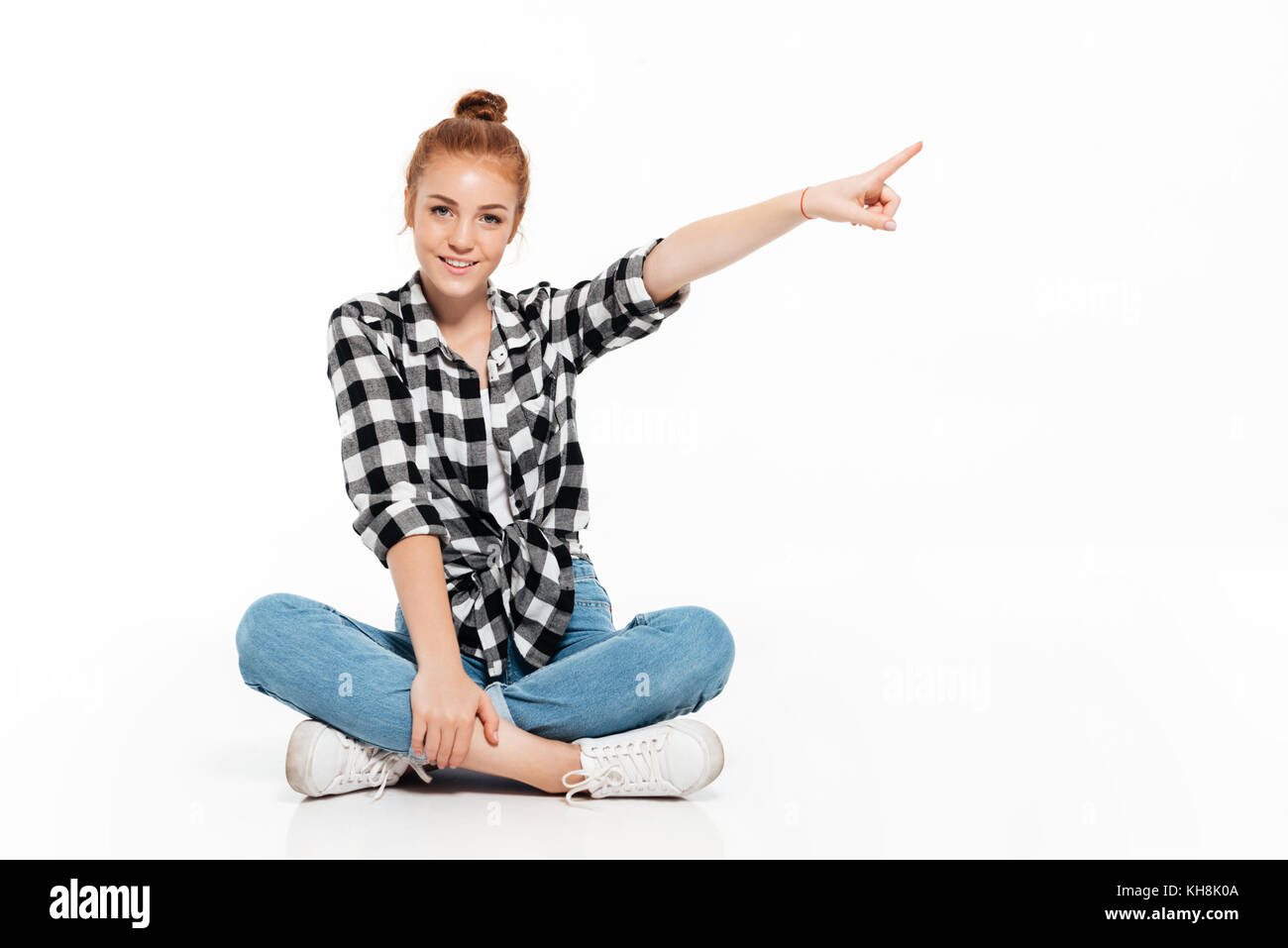 Pleased ginger woman in shirt and jeans sitting on the floor and ...