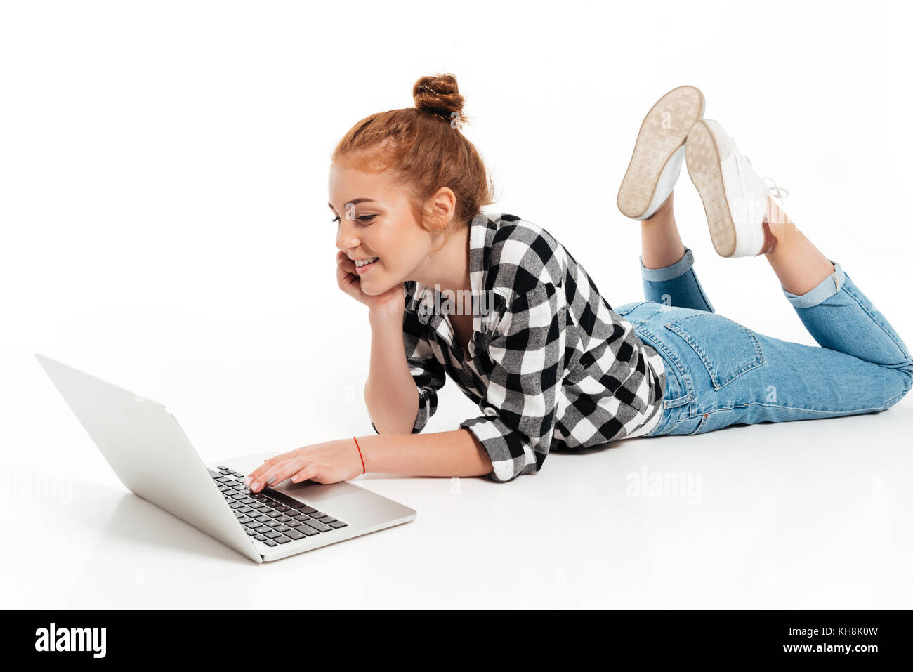 Happy ginger woman in shirt and jeans lying on the floor and using ...