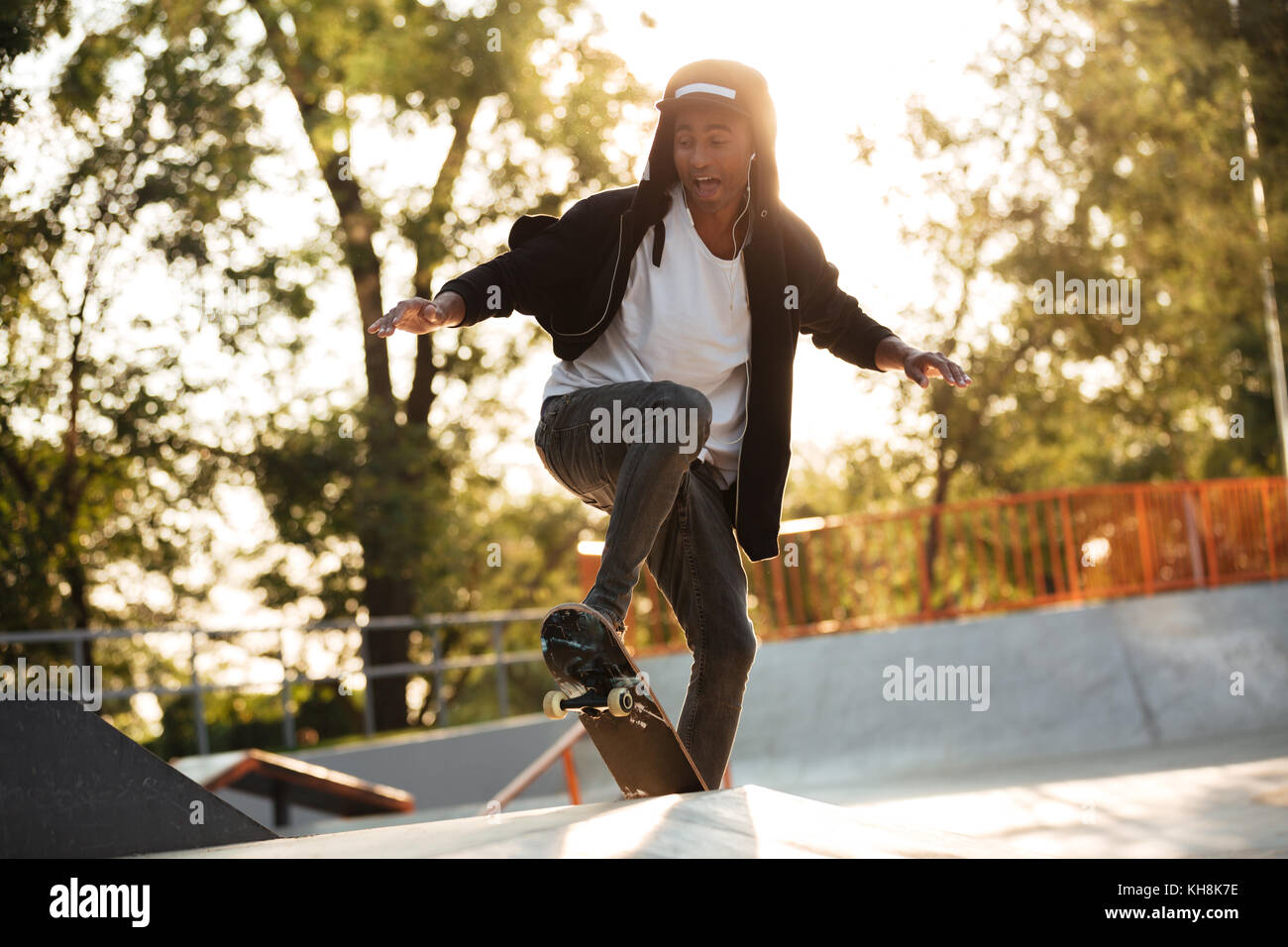 Afro american guy jumping with his skate and performing a trick Stock Photo