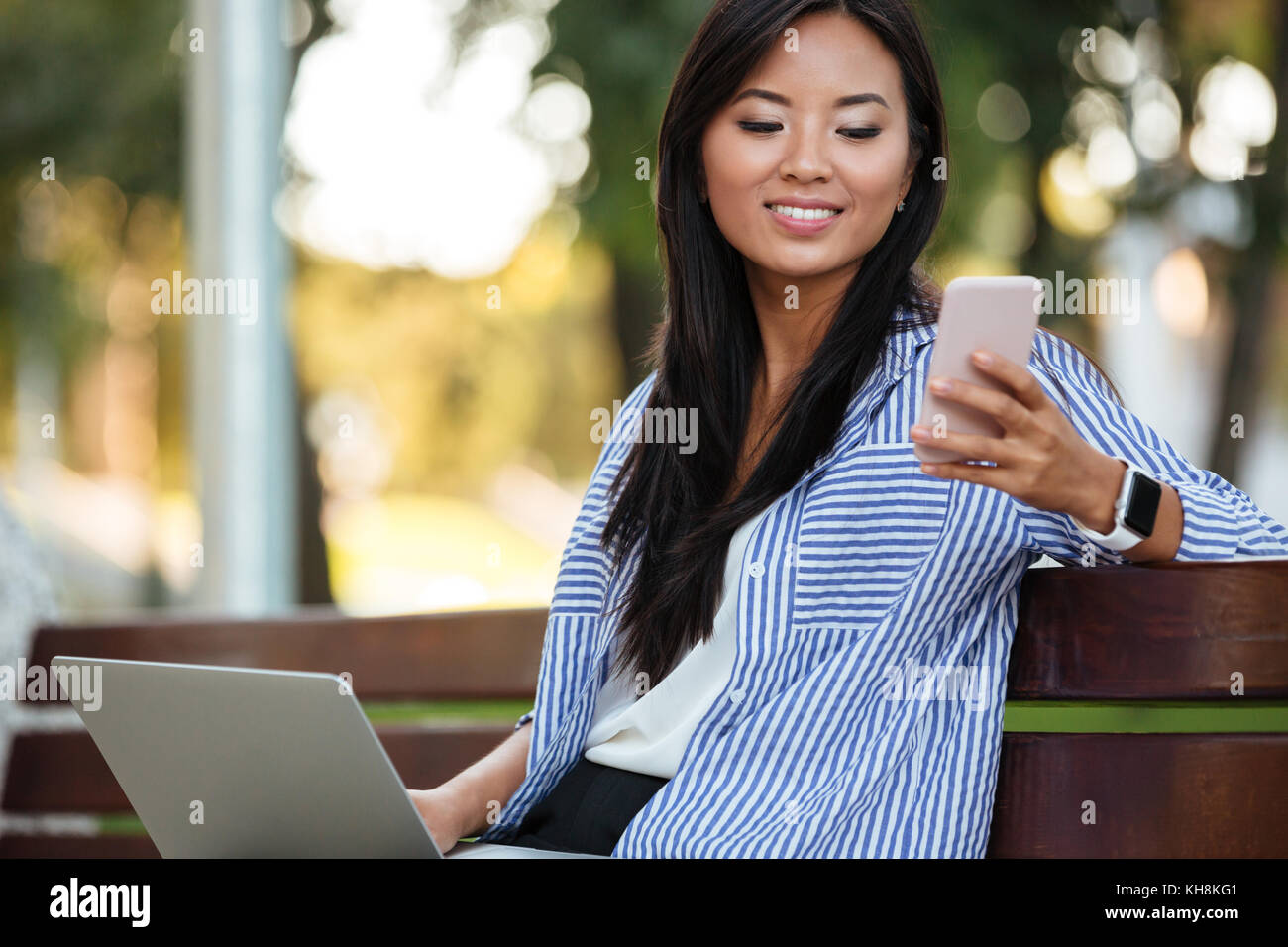 Portrait of a smiling pretty asian female student holding laptop ...
