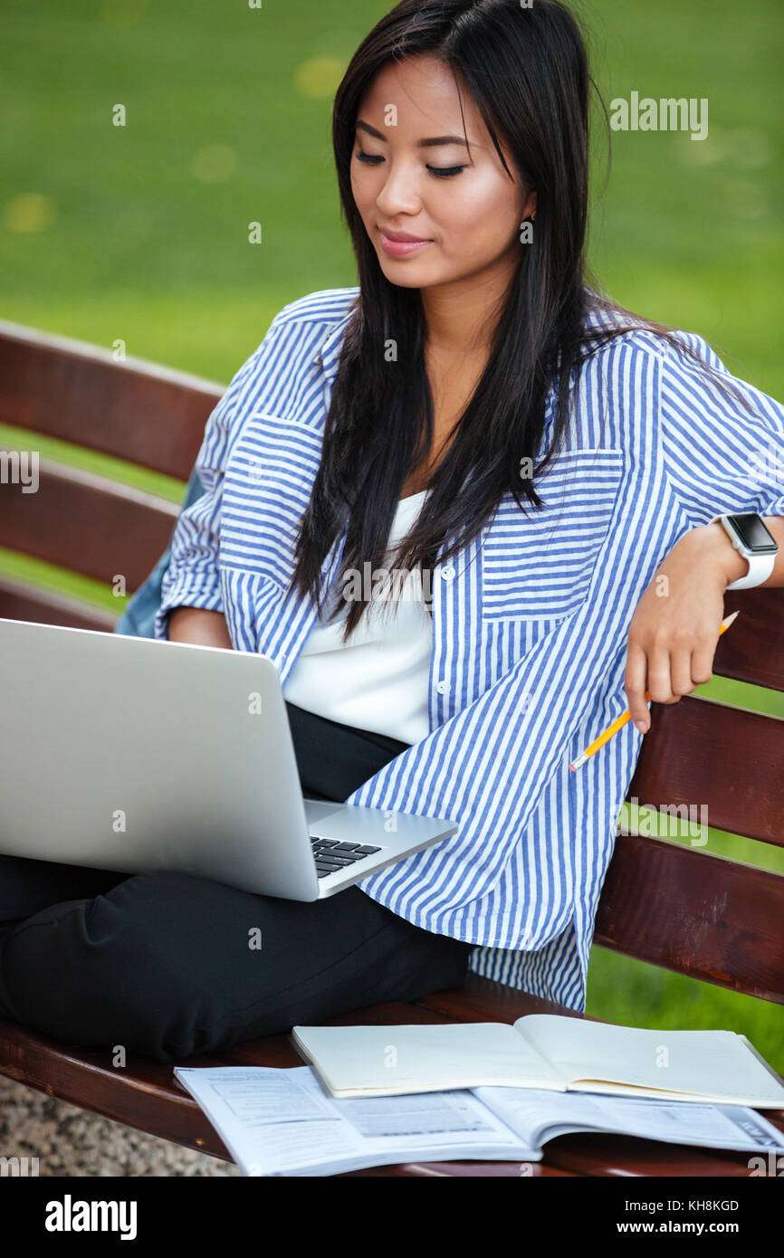 Portrait of a beautiful smart asian female student studying with laptop ...