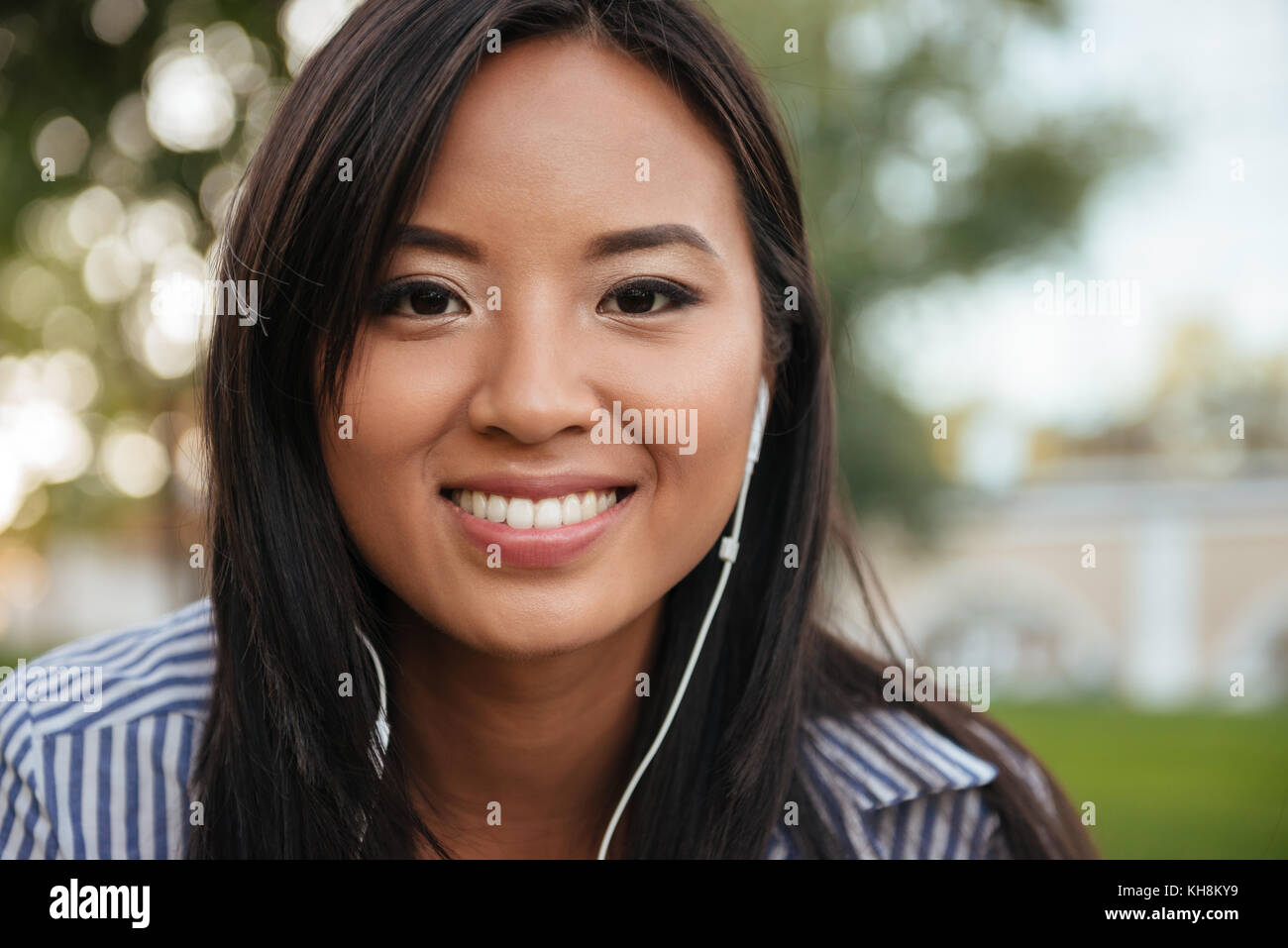 Close-up photo of young cheerful asian woman listening to music ...