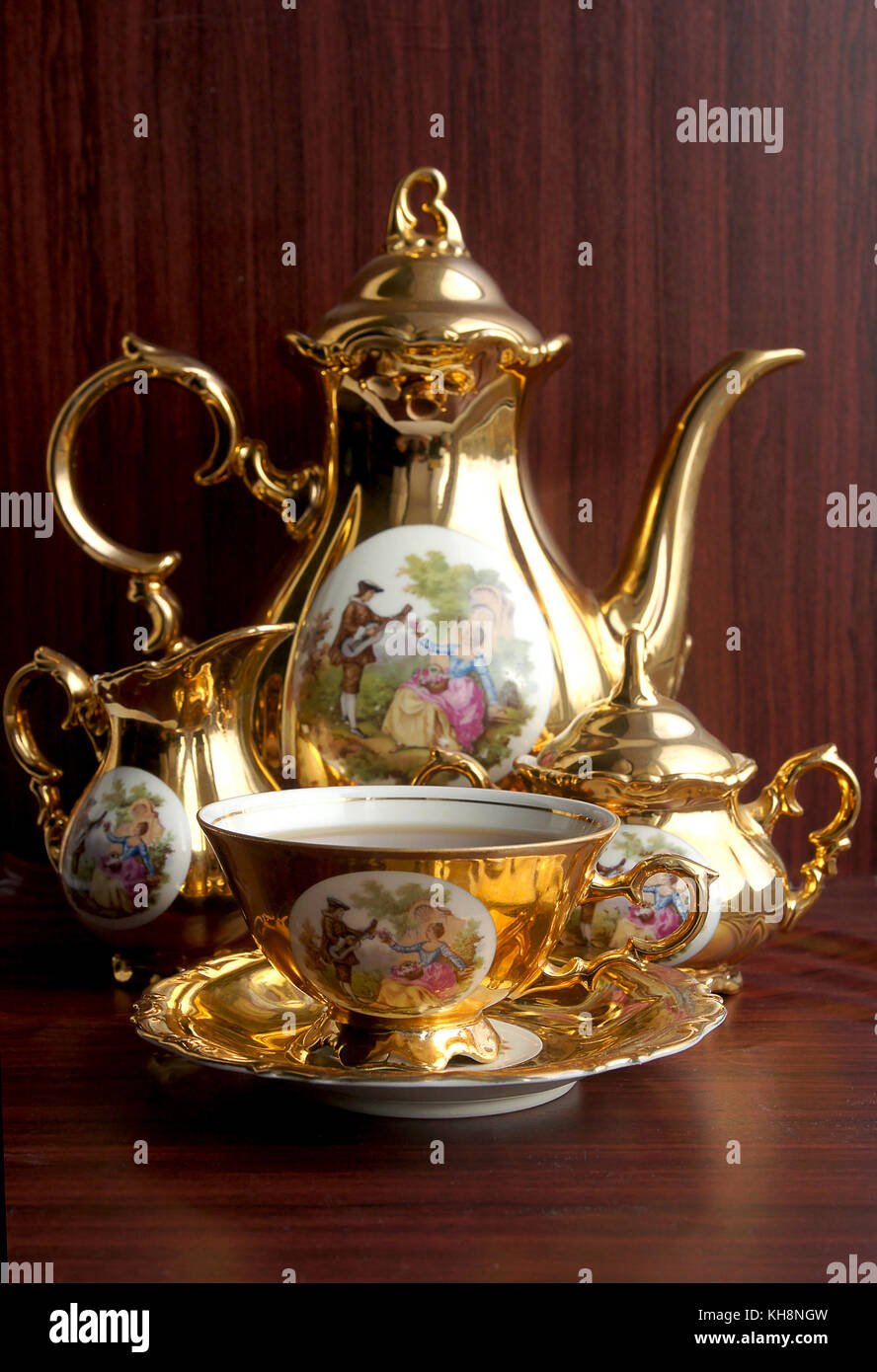 Beautiful vintage gold tea service with pictures on wood background